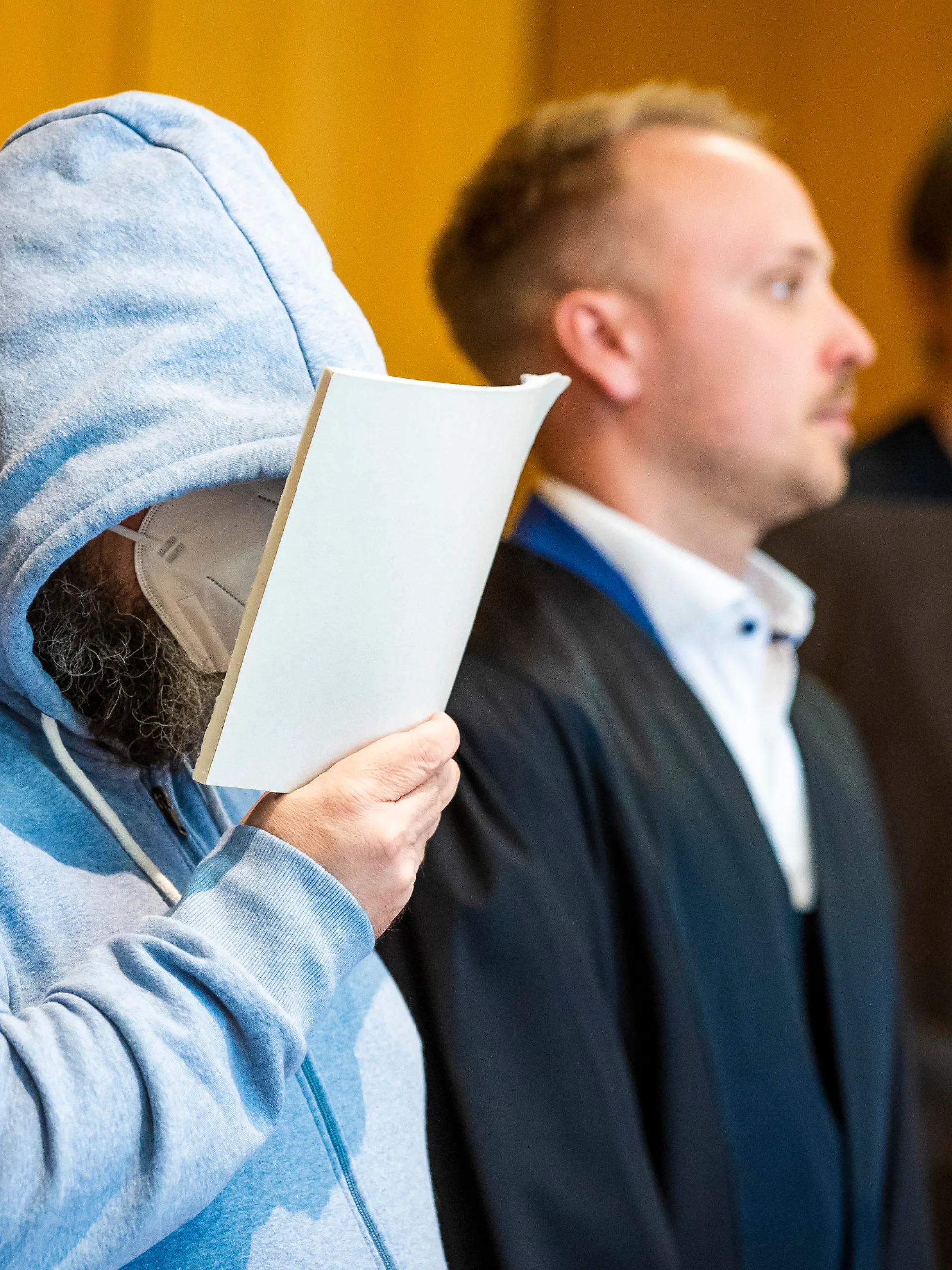 19.06.2023, Niedersachsen, Hildesheim: Der Angeklagte (l) steht beim Prozessauftakt wegen teils schweren sexuellen Missbrauchs von Kindern neben seinem Verteidiger Jonas Meese (M) in einem Saal des Landgerichts Hildesheim. Dem Angeklagten wird vorgeworfen, sich gegenüber Eltern als vertrauenswürdige Aufsichtsperson ausgegeben und dann in seiner Wohnung insgesamt 16 Straftaten begangen zu haben. Die betroffenen Kinder sollen nach Gerichtsangaben etwa zwischen fünf und zwölf Jahre alt gewesen sein. Foto: Moritz Frankenberg/dpa +++ dpa-Bildfunk +++