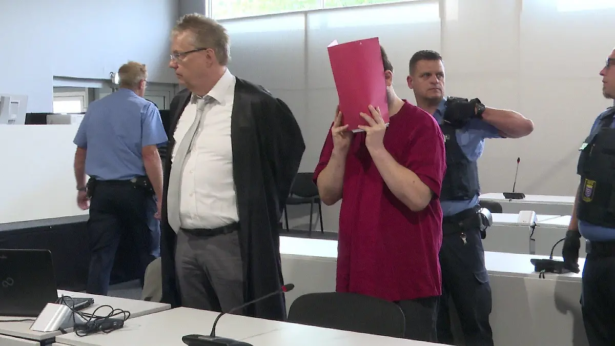 Jan Heiko P. hält sich im Gerichtssaal einen Ordner vor das Gesicht