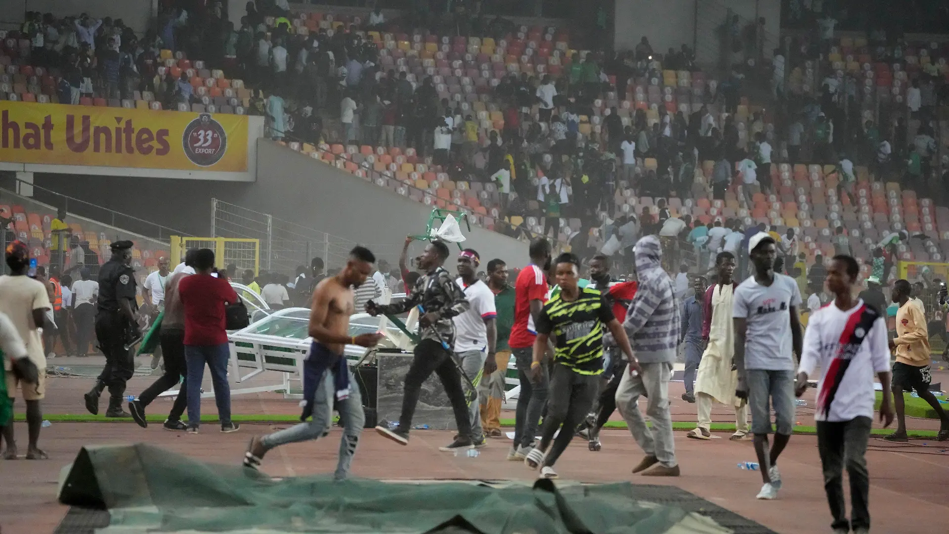 29.03.2022, Nigeria, Abuja: Fußball: WM-Qualifikation, Afrika, Nigeria - Ghana, M.K.O Abiola National Stadium Abuja: Die Polizei feuert Tränengas ab, um Fußball-Fans auseinanderzutreiben die das Spielfeld stürmten. Nach dem Aus der nigerianischen Fußball-Nationalmannschaft im entscheidenden WM-Qualifikationsspiel gegen Ghana ist es zu gewalttätigen Ausschreitungen gekommen. Foto: Sunday Alamba/AP/dpa +++ dpa-Bildfunk +++