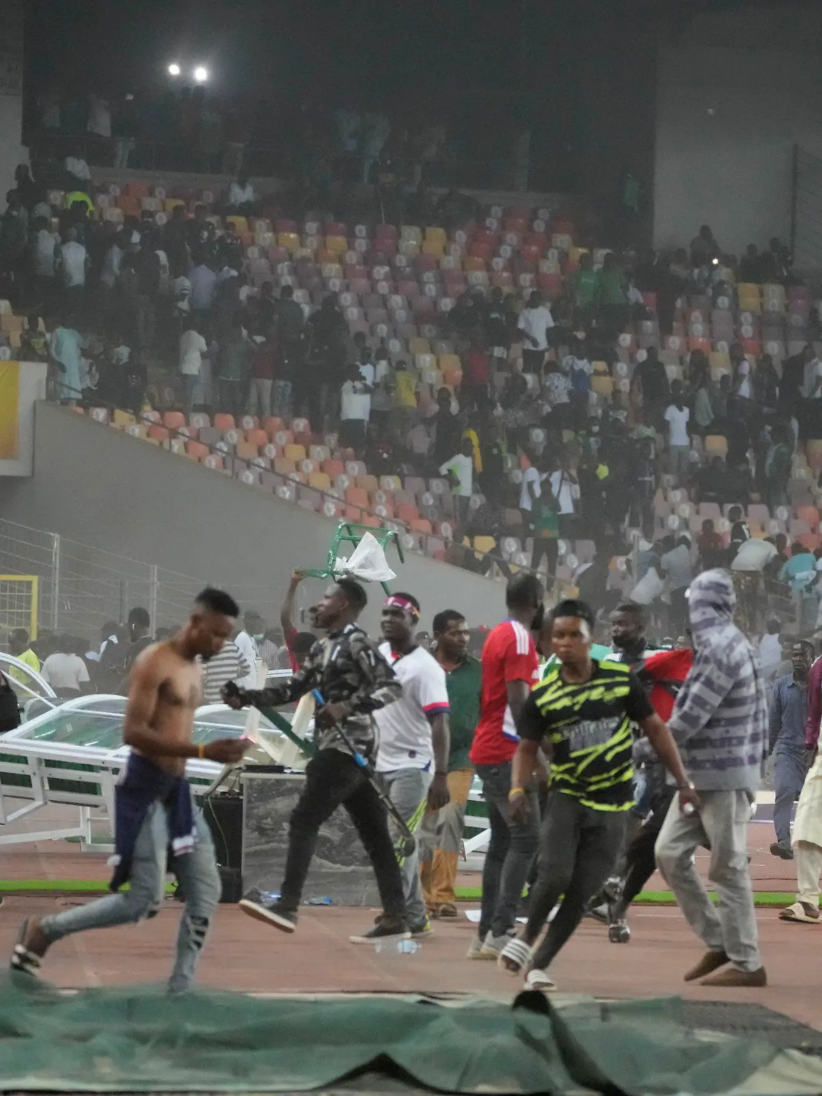 29.03.2022, Nigeria, Abuja: Fußball: WM-Qualifikation, Afrika, Nigeria - Ghana, M.K.O Abiola National Stadium Abuja: Die Polizei feuert Tränengas ab, um Fußball-Fans auseinanderzutreiben die das Spielfeld stürmten. Nach dem Aus der nigerianischen Fußball-Nationalmannschaft im entscheidenden WM-Qualifikationsspiel gegen Ghana ist es zu gewalttätigen Ausschreitungen gekommen. Foto: Sunday Alamba/AP/dpa +++ dpa-Bildfunk +++