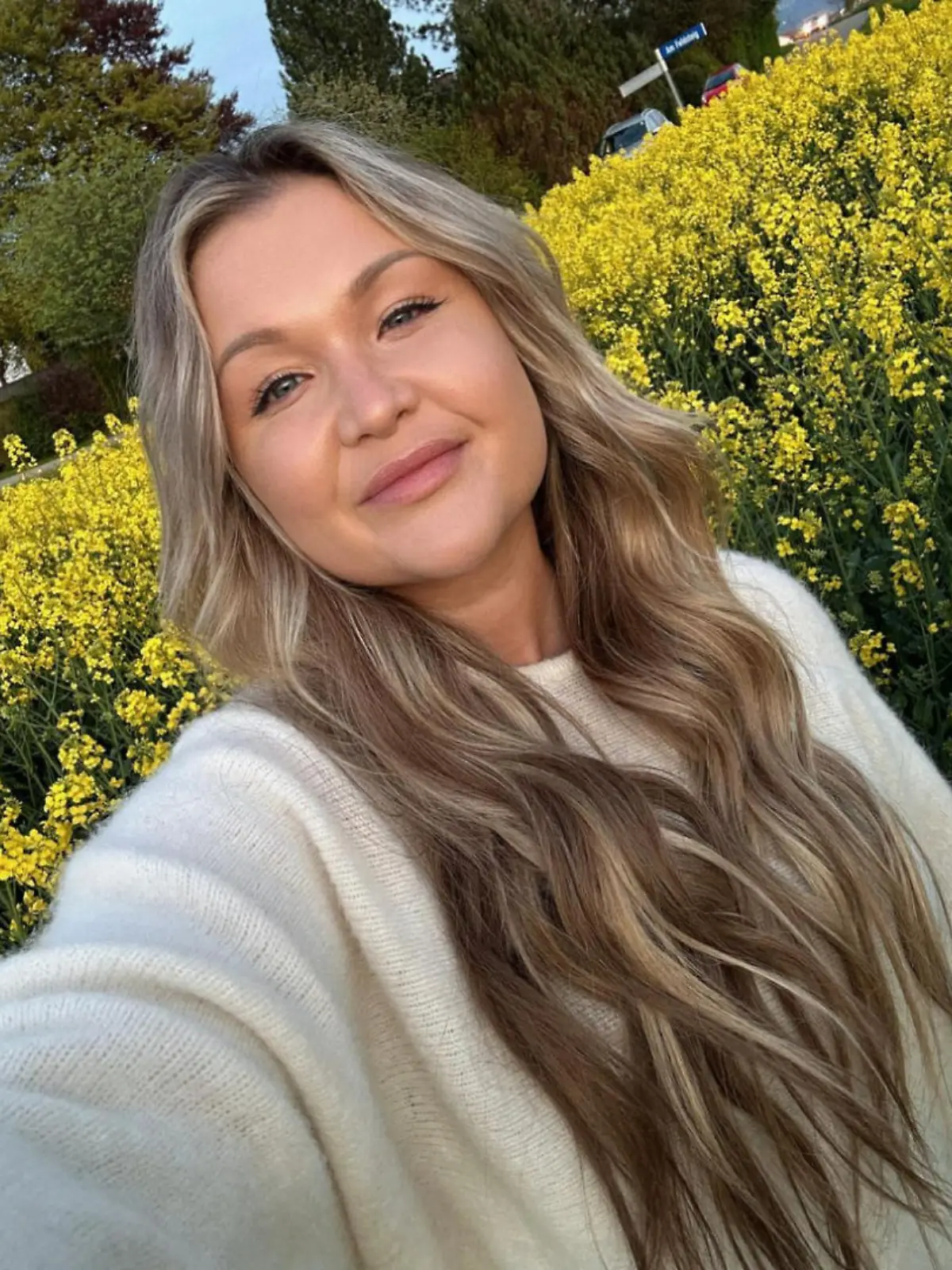 Sophia Thiel steht in einem Rapsfeld und macht ein Selfie. Sie lächelt in die Kamera.