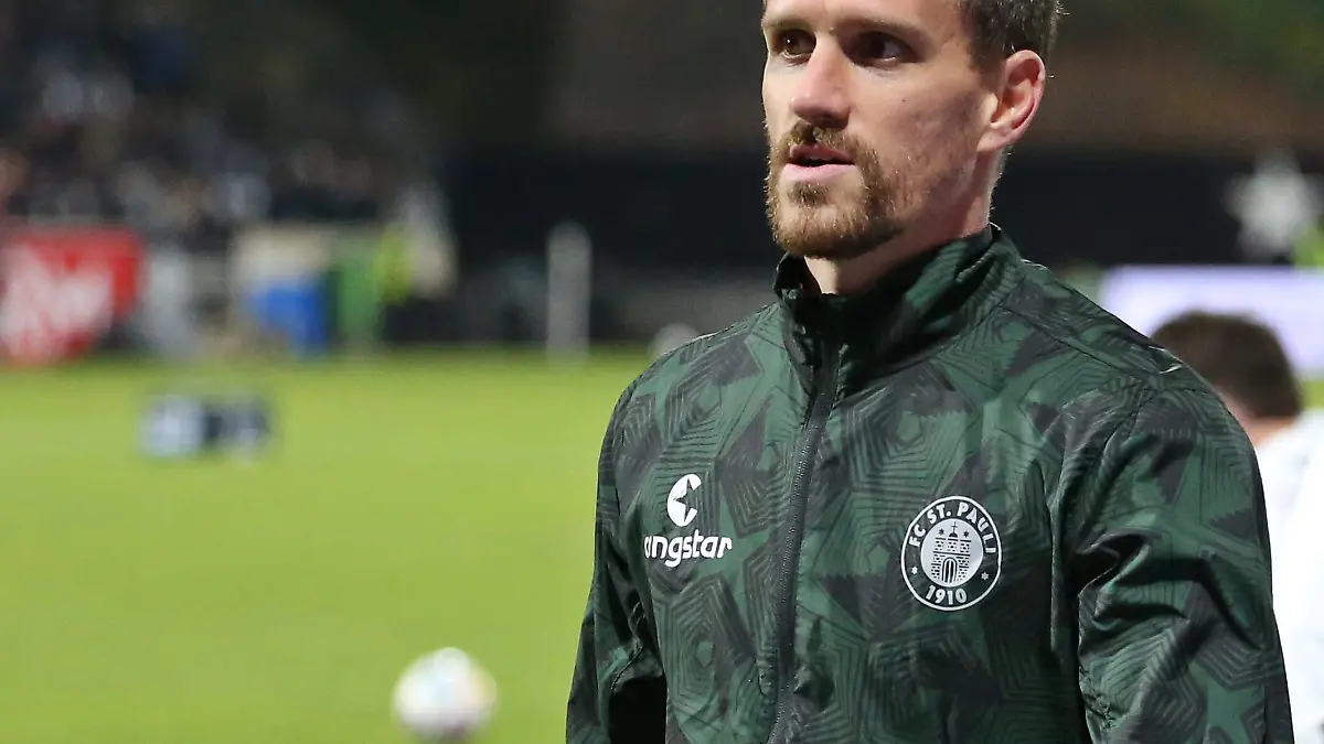 Simon Zoller (FC St. Pauli) läuft in Trainingsjacke über den Platz