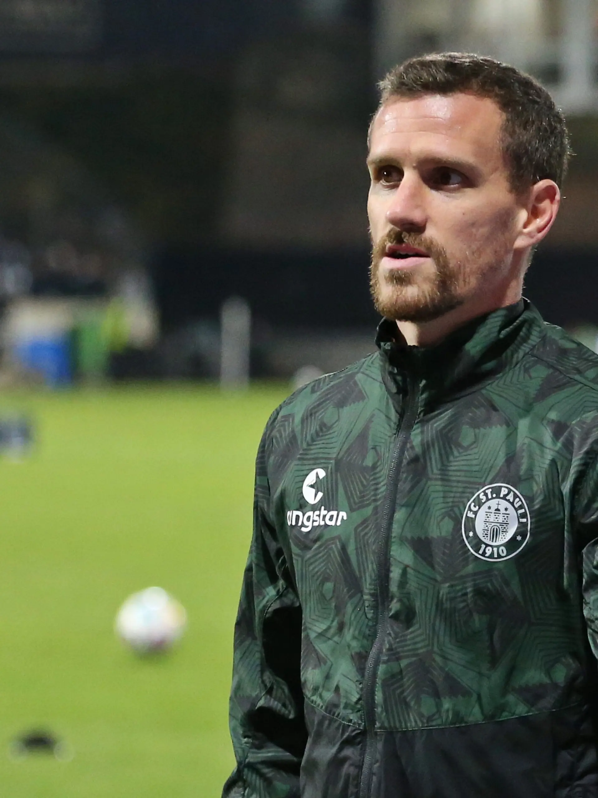 Simon Zoller (FC St. Pauli) läuft in Trainingsjacke über den Platz