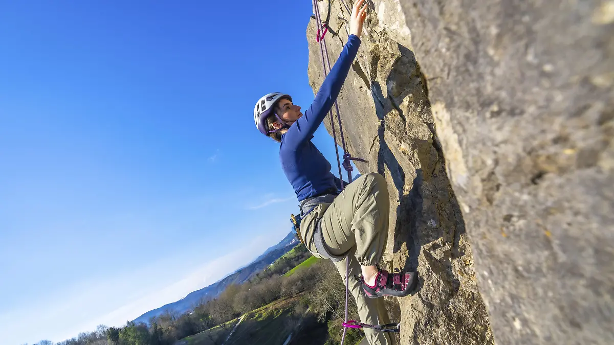 Eine Bergsteigerin klettert an einem Felsen