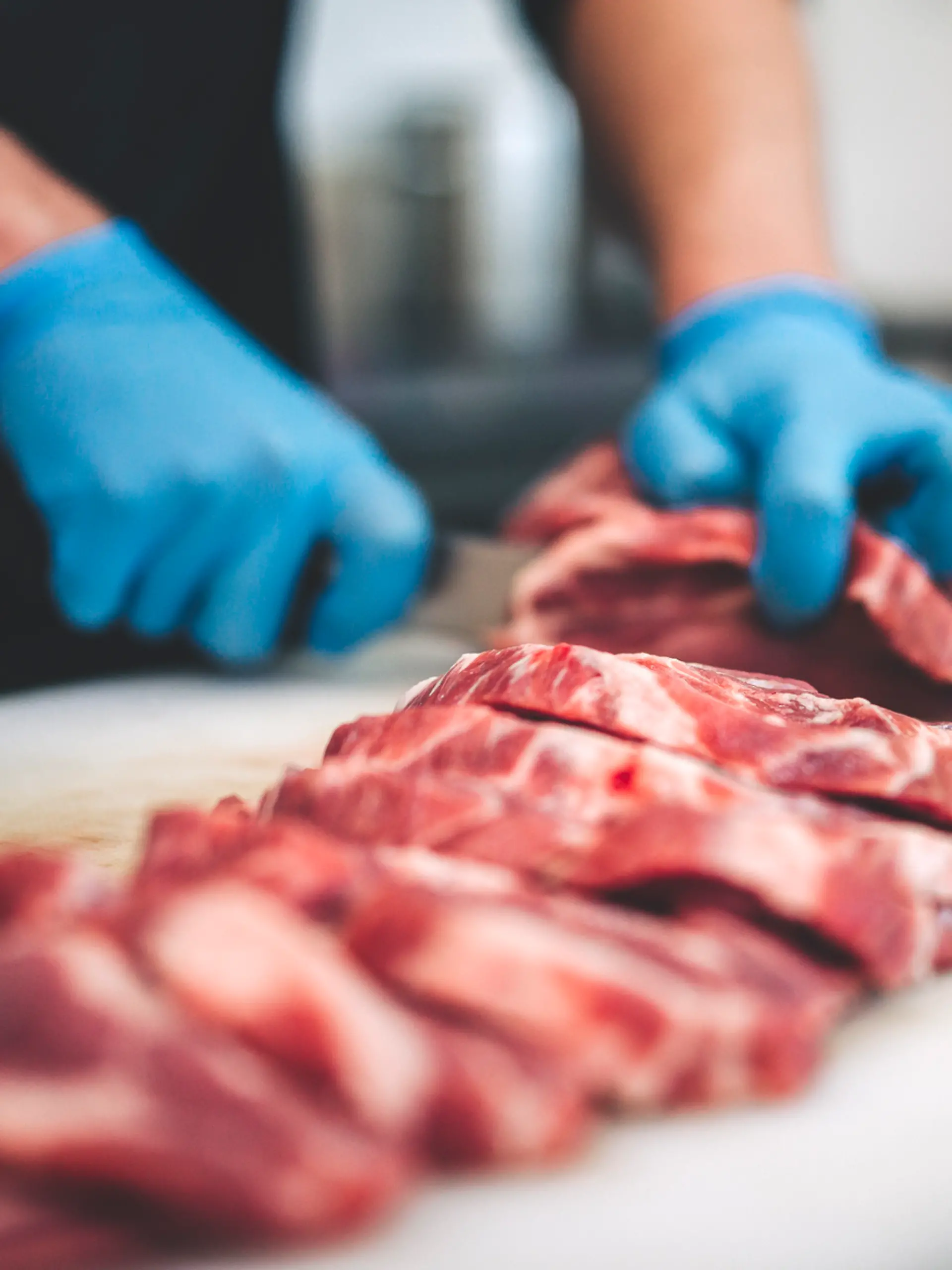Ein Mann schneidet Fleisch in einer Küche.