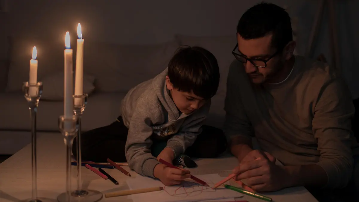 Child and Father Painting By Candlelight During A Power Outage