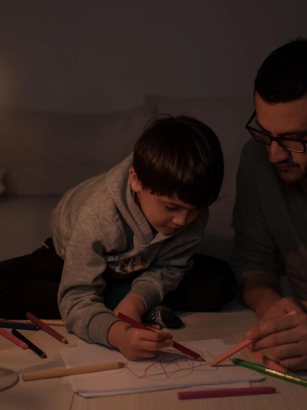 Child and Father Painting By Candlelight During A Power Outage