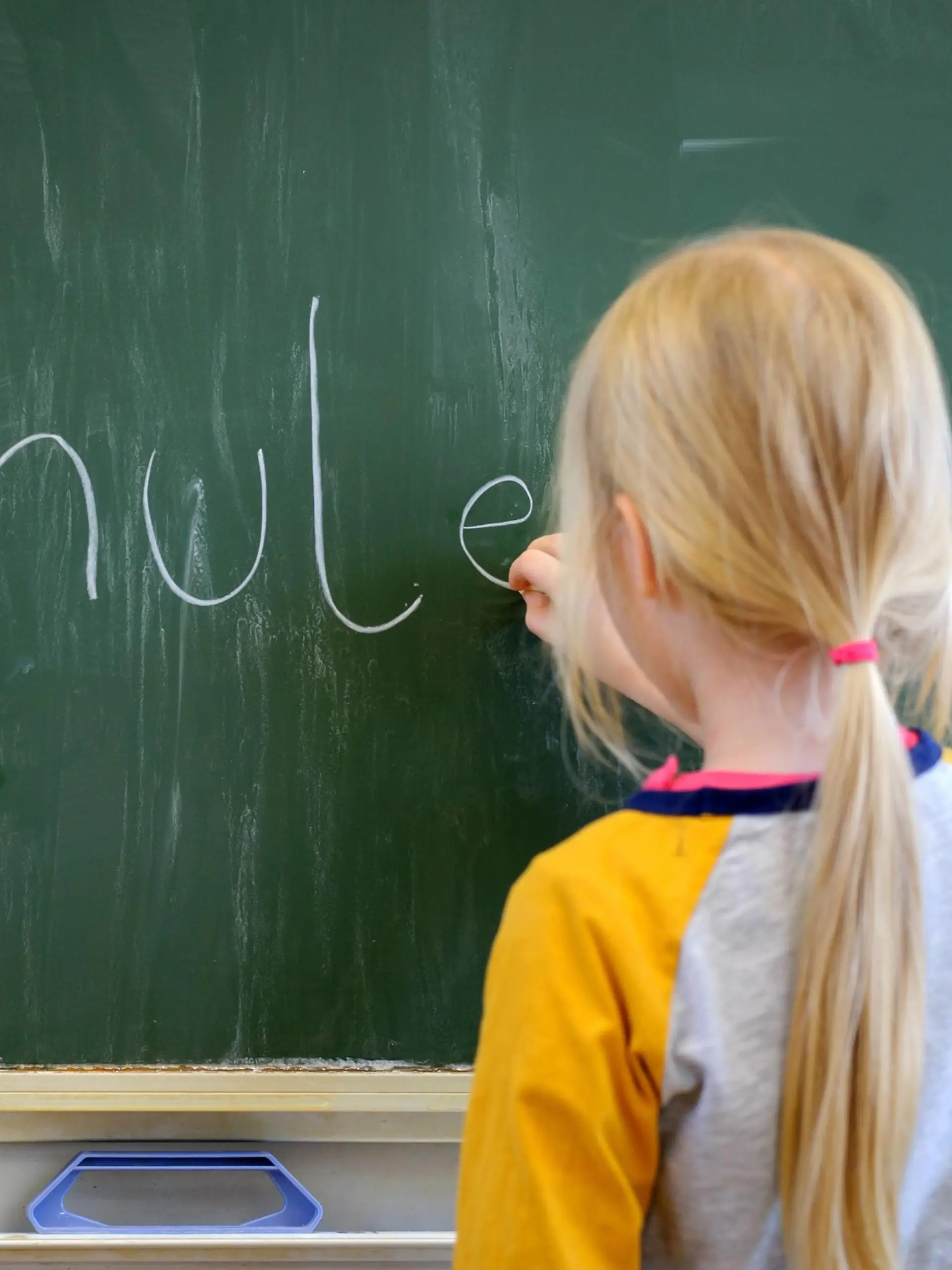  Ein Schulkind schreibt mit Kreide an eine Schultafel den Satz Schule ist schön , aufgenommen am 19.01.2015 in Dresden.
