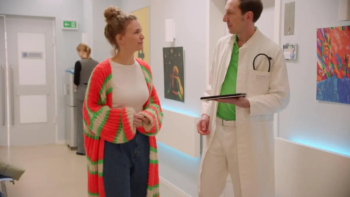 Als Zoe (Lara Dandelion Seibert, hinten) angespannt Dr. Thieß (Peter Wagner) bemerkt, der gemeinsam mit Paulina Wendland (Christina Arends) aus einem Krankenzimmer tritt, versteckt sie sich kurzum. Ihr wird klar, dass in dem Zimmer Clara liegen muss. Wird Zoe gleich ihre Tochter allein sehen?