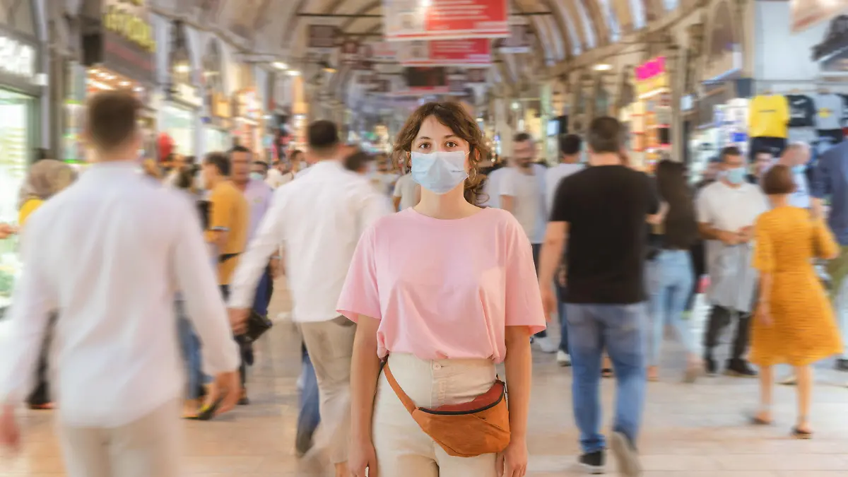 Young Caucasian woman in mask standing in the crowd on Grand Bazaar in Istanbul