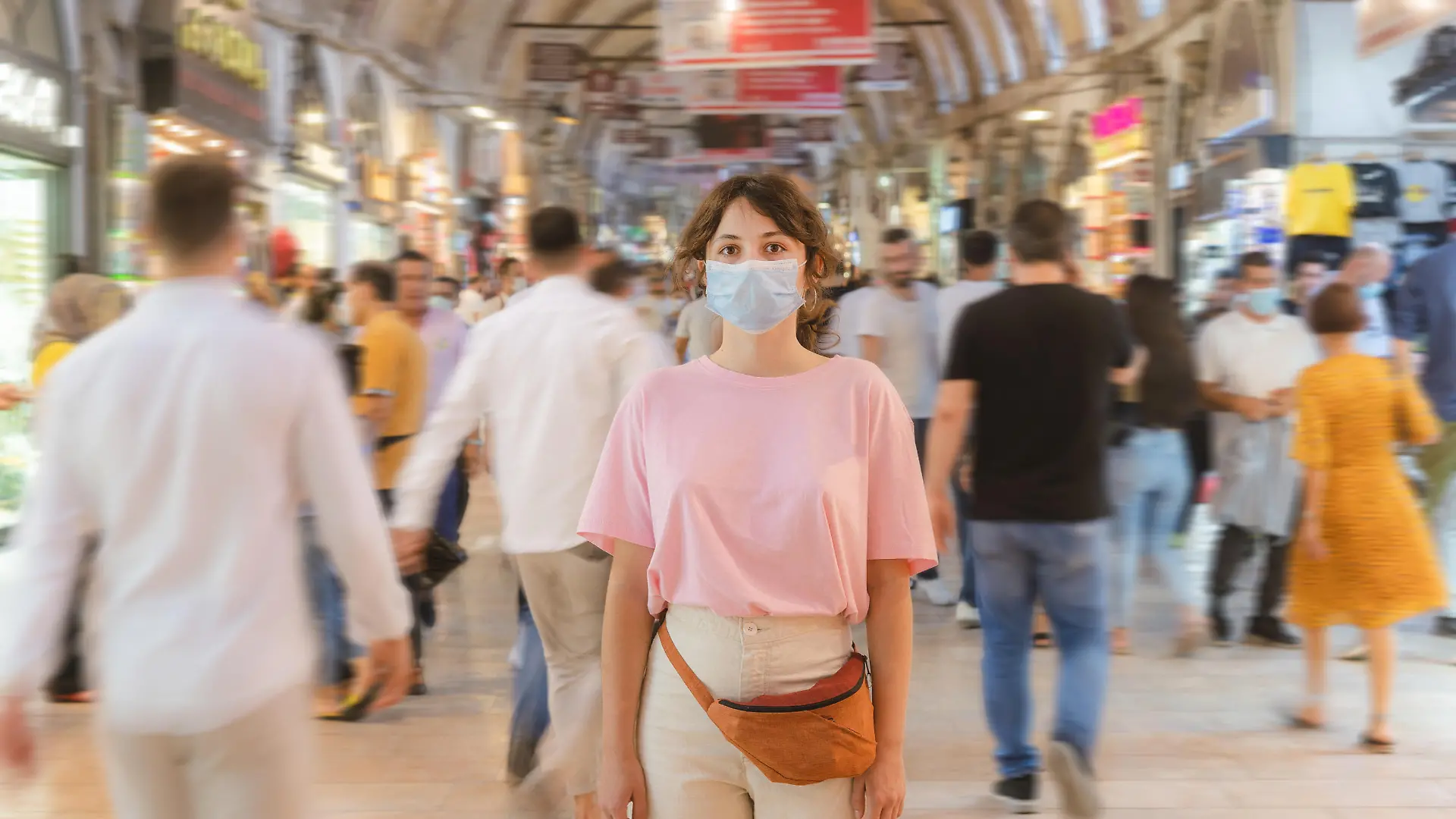 Young Caucasian woman in mask standing in the crowd on Grand Bazaar in Istanbul