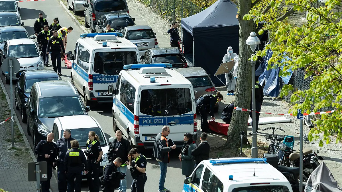 Polizisten und Beamte der Spurensicherung in weißen Schutzanzügen stehen an dem Ort, wo ein toter Mann gefunden wurde.