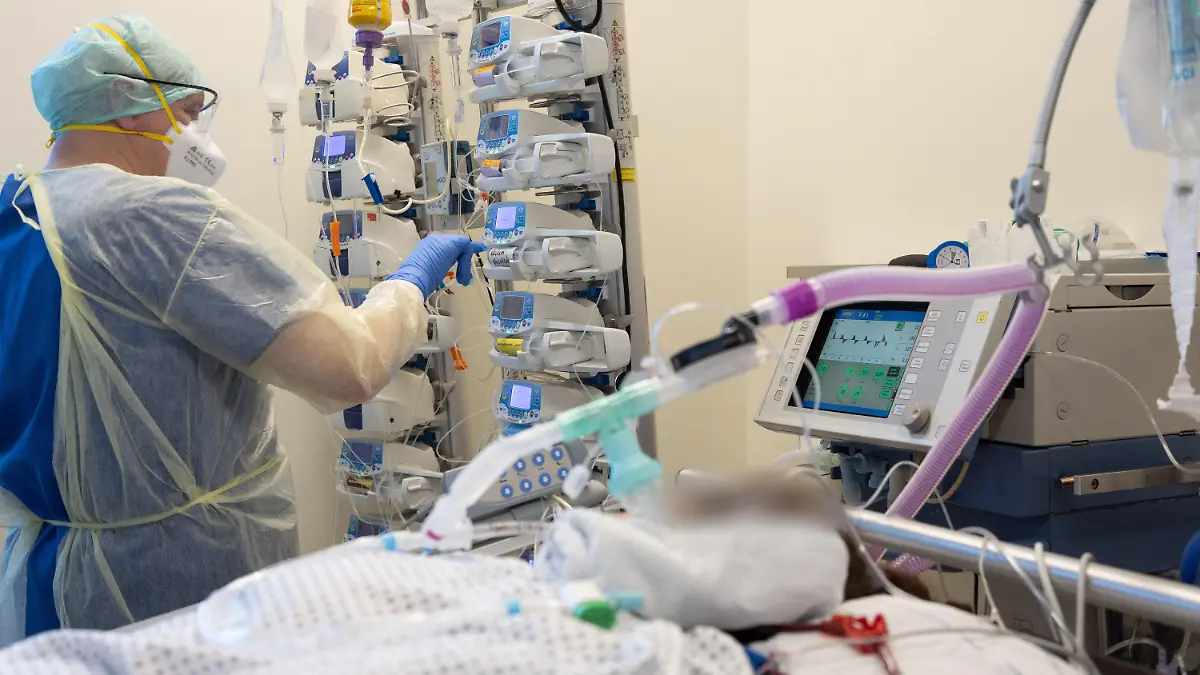 25.03.2022, Niedersachsen, Osnabrück: Ein Krankenpfleger versorgt einen schwer an Corona erkrankten Patienten auf der Intensivstation von einem Krankenhaus. Der Patient ist an Perfusoren angeschlossen und wird künstlich beatmet. Viele Patienten mit schweren Verläufen liegen mehrere Wochen auf der Intensivstation, rund die Hälfte der künstlich beatmeten Patienten stirbt. Foto: Friso Gentsch/dpa - ACHTUNG: Person(en) wurde(n) aus rechtlichen Gründen gepixelt +++ dpa-Bildfunk +++