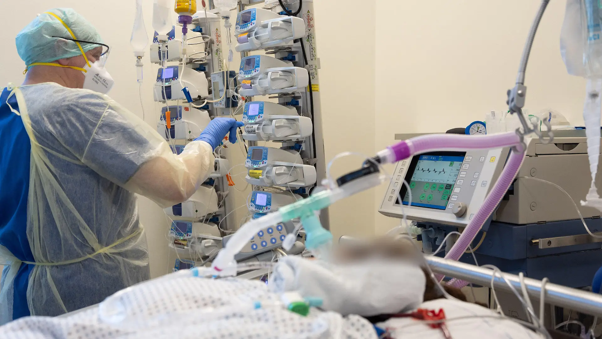25.03.2022, Niedersachsen, Osnabrück: Ein Krankenpfleger versorgt einen schwer an Corona erkrankten Patienten auf der Intensivstation von einem Krankenhaus. Der Patient ist an Perfusoren angeschlossen und wird künstlich beatmet. Viele Patienten mit schweren Verläufen liegen mehrere Wochen auf der Intensivstation, rund die Hälfte der künstlich beatmeten Patienten stirbt. Foto: Friso Gentsch/dpa - ACHTUNG: Person(en) wurde(n) aus rechtlichen Gründen gepixelt +++ dpa-Bildfunk +++
