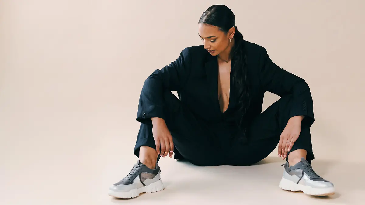Studio shot of a beautiful young woman sitting on the floor against a brown background