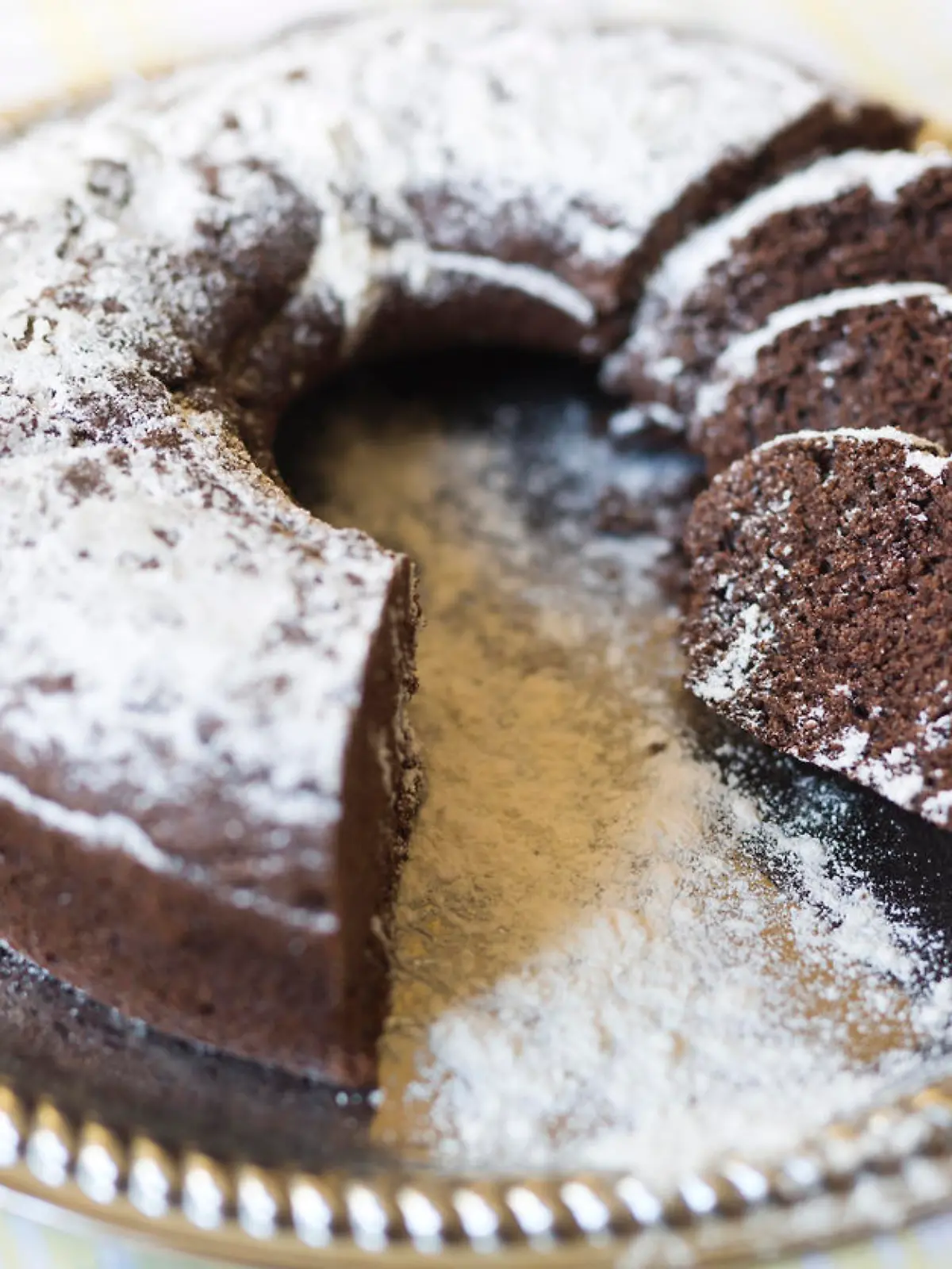 Homemade chocolate cake, with sugar glass on top, on a golden tray. Horizontal shot with natural light from a window.