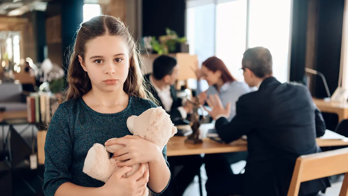 Sad girl stands with a bear in the office. The family came to the lawyer in the office and found out that they had lost the case in court.