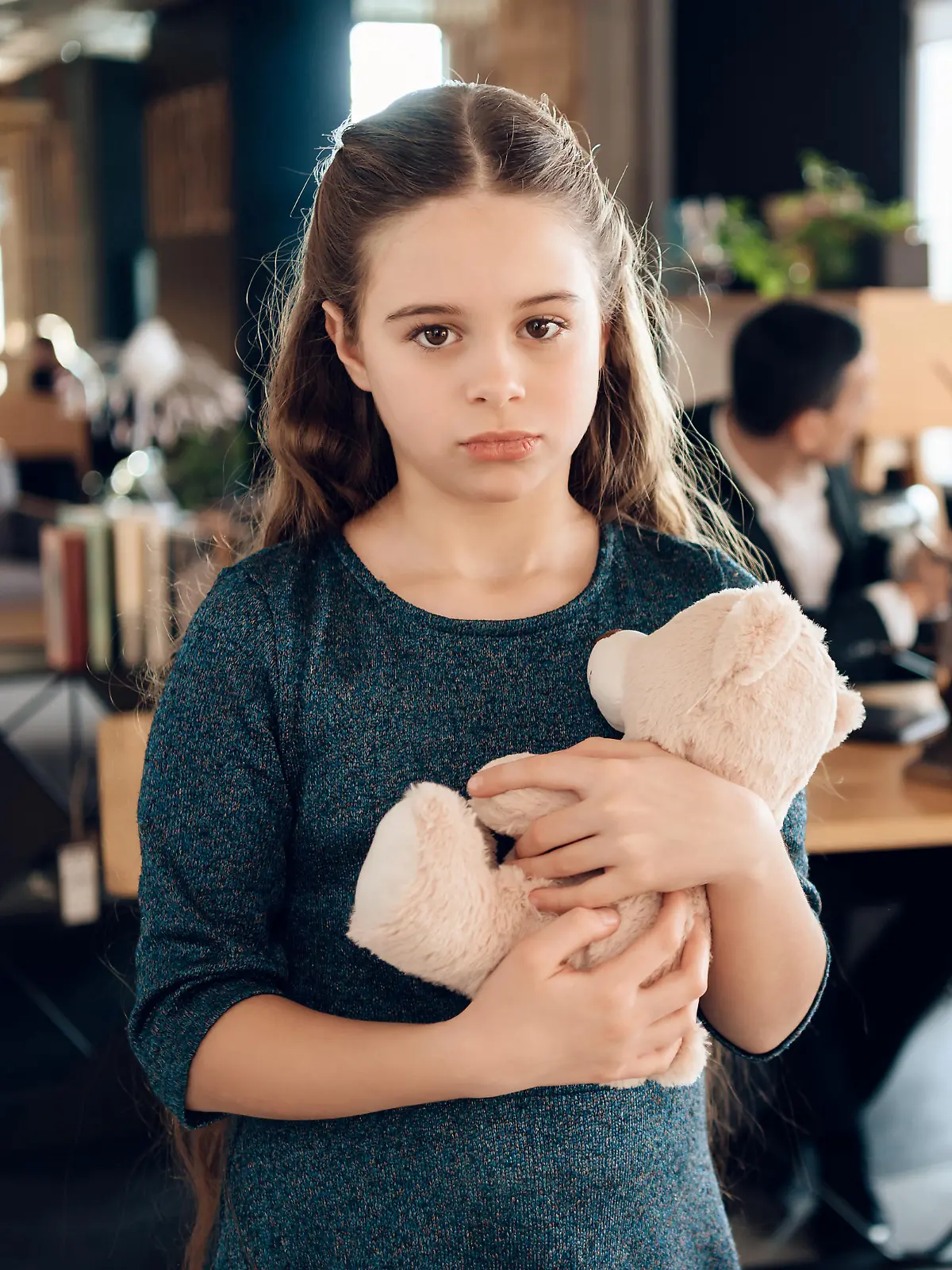 Sad girl stands with a bear in the office. The family came to the lawyer in the office and found out that they had lost the case in court.