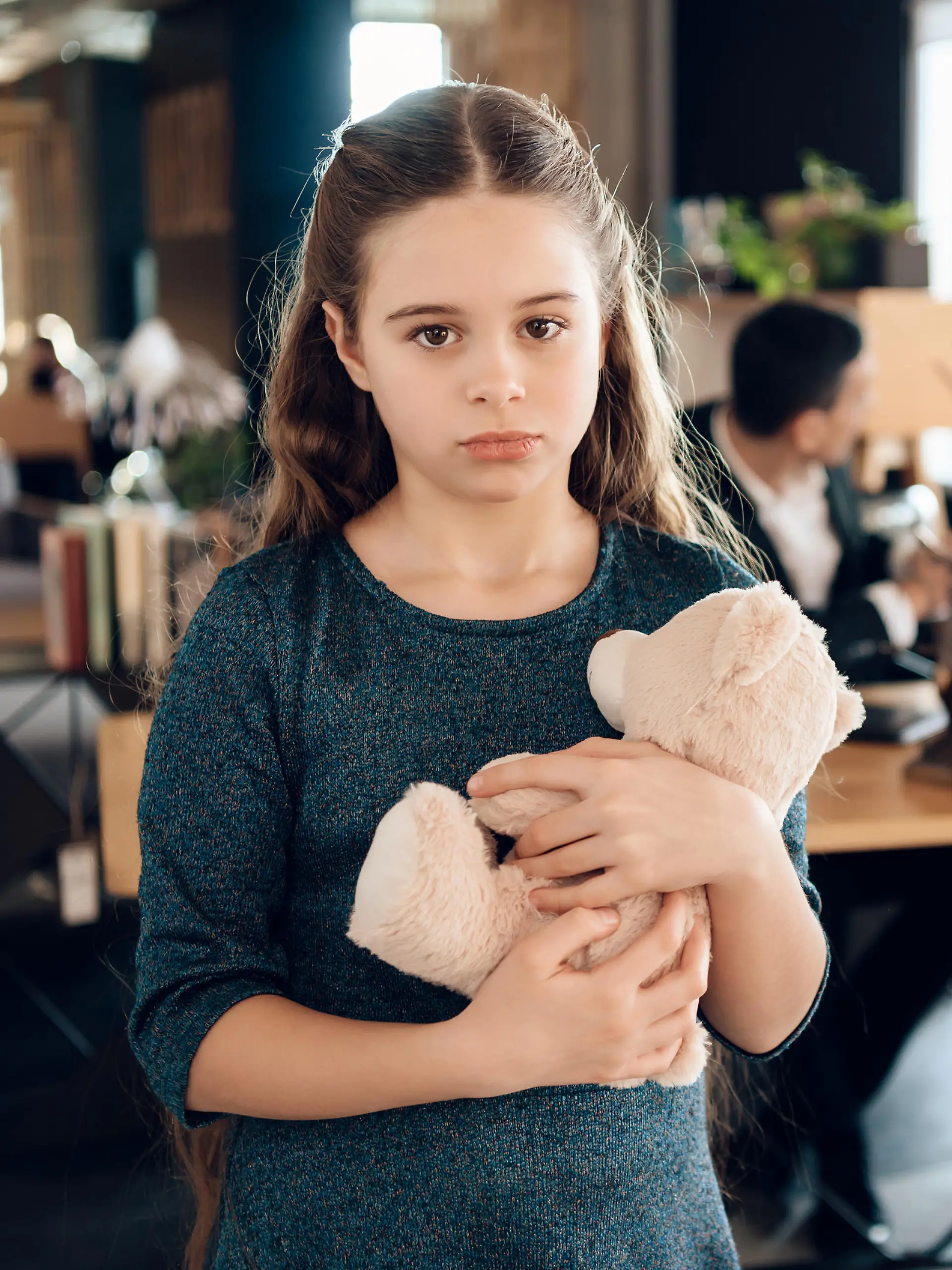 Sad girl stands with a bear in the office. The family came to the lawyer in the office and found out that they had lost the case in court.