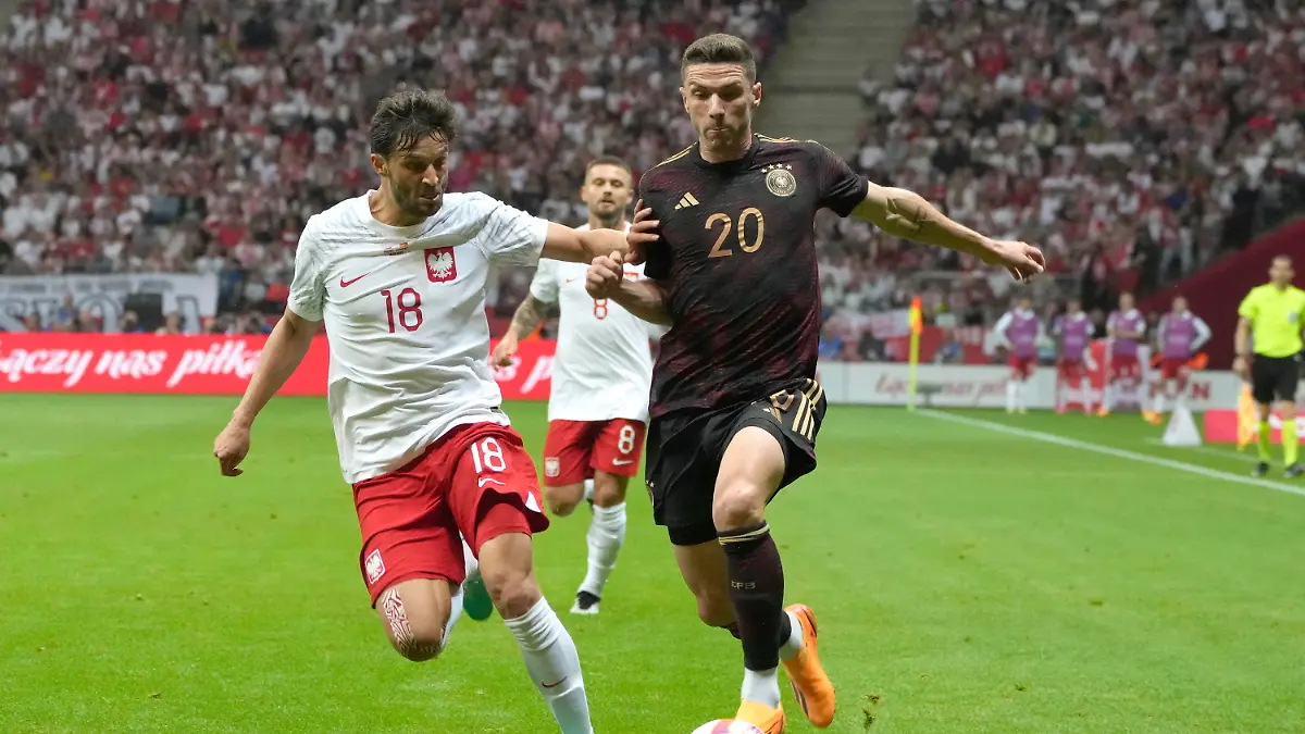 Poland' Bartosz Bereszynski, left, challenges for the ball with Germany's Robin Gosens during the international friendly soccer match between Poland and Germany at the Narodowy stadium in Warsaw, Poland, Friday, June 16, 2023. (AP Photo/Czarek Sokolowski)