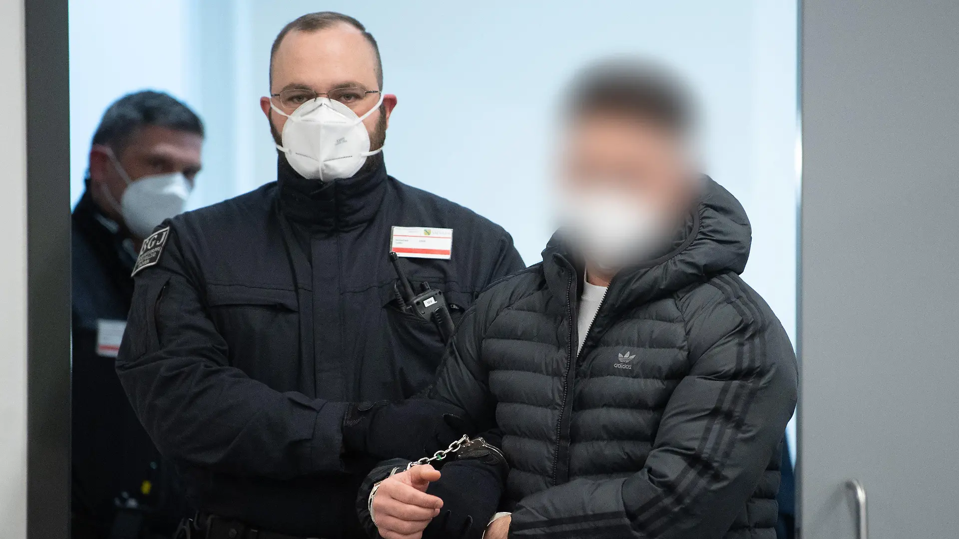 29.03.2022, Sachsen, Dresden: Ein Angeklagter (r) im Prozess um den Juwelenraub im Grünen Gewölbe wird bei der Fortsetzung des Prozess in den Verhandlungssaal im Landgericht geführt. Foto: Sebastian Kahnert/dpa-Zentralbild/Pool/dpa - ACHTUNG: Der Angeklagte wurde auf Anweisung des Gerichts gepixelt +++ dpa-Bildfunk +++
