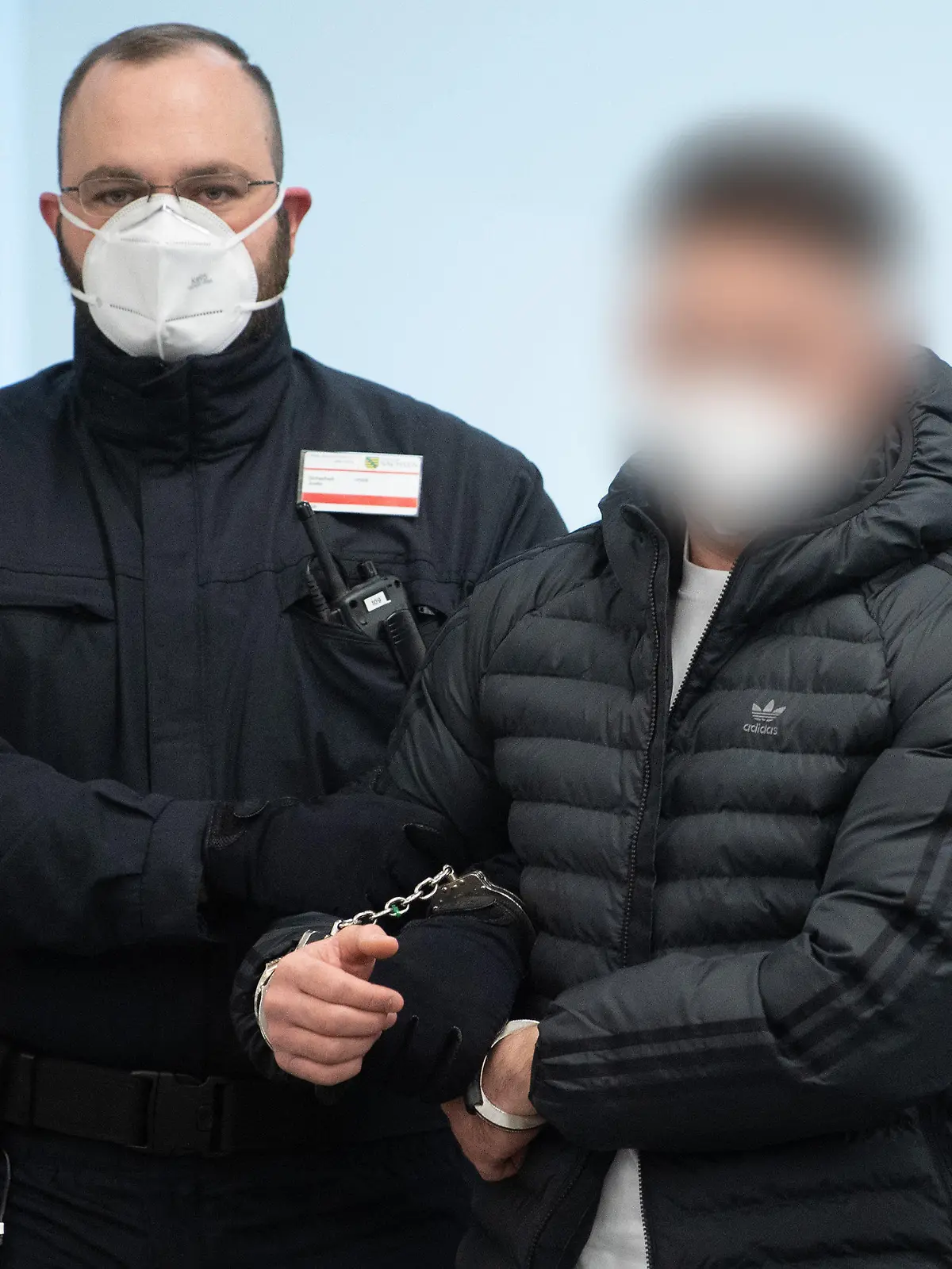 29.03.2022, Sachsen, Dresden: Ein Angeklagter (r) im Prozess um den Juwelenraub im Grünen Gewölbe wird bei der Fortsetzung des Prozess in den Verhandlungssaal im Landgericht geführt. Foto: Sebastian Kahnert/dpa-Zentralbild/Pool/dpa - ACHTUNG: Der Angeklagte wurde auf Anweisung des Gerichts gepixelt +++ dpa-Bildfunk +++