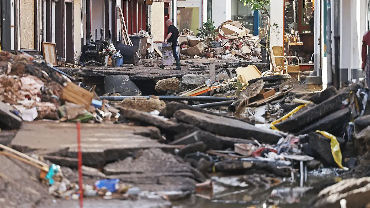 18.07.2021, Nordrhein-Westfalen, Bad Münstereifel: Ein Mann trägt Trümmer aus dem Haus. In Bad Münstereifel hat die über die Ufer getretene Erft erhebliche Schäden angerichtet. Foto: Oliver Berg/dpa +++ dpa-Bildfunk +++