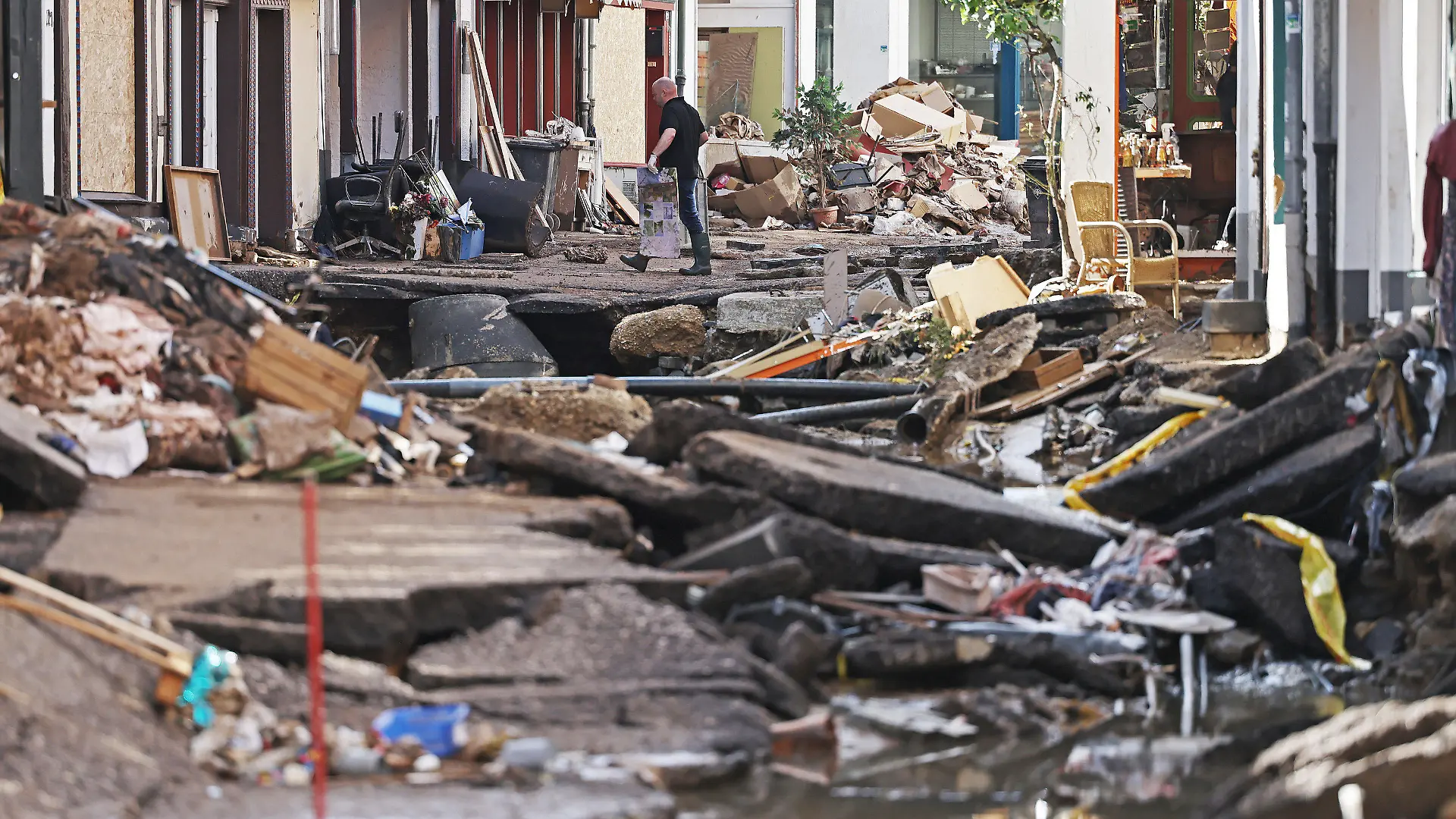 18.07.2021, Nordrhein-Westfalen, Bad Münstereifel: Ein Mann trägt Trümmer aus dem Haus. In Bad Münstereifel hat die über die Ufer getretene Erft erhebliche Schäden angerichtet. Foto: Oliver Berg/dpa +++ dpa-Bildfunk +++