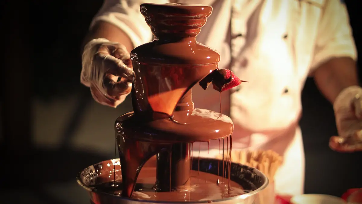 Chef is preparing a strawberry skewer under a chocolate fountain/ Schokoladenbrunnen