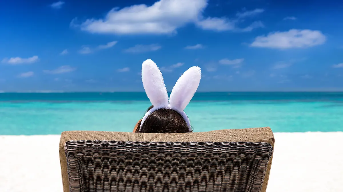 Easter travel concept: Woman with bunny ears on a tropical beach