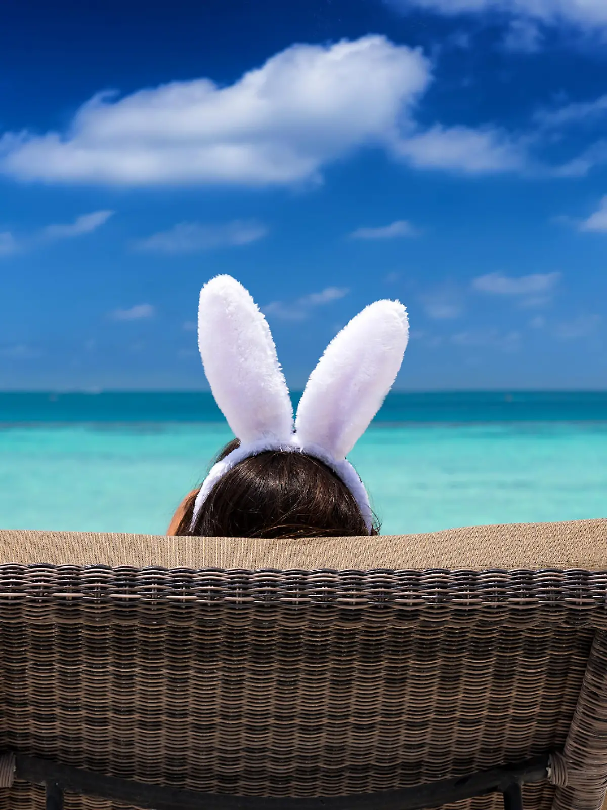 Easter travel concept: Woman with bunny ears on a tropical beach
