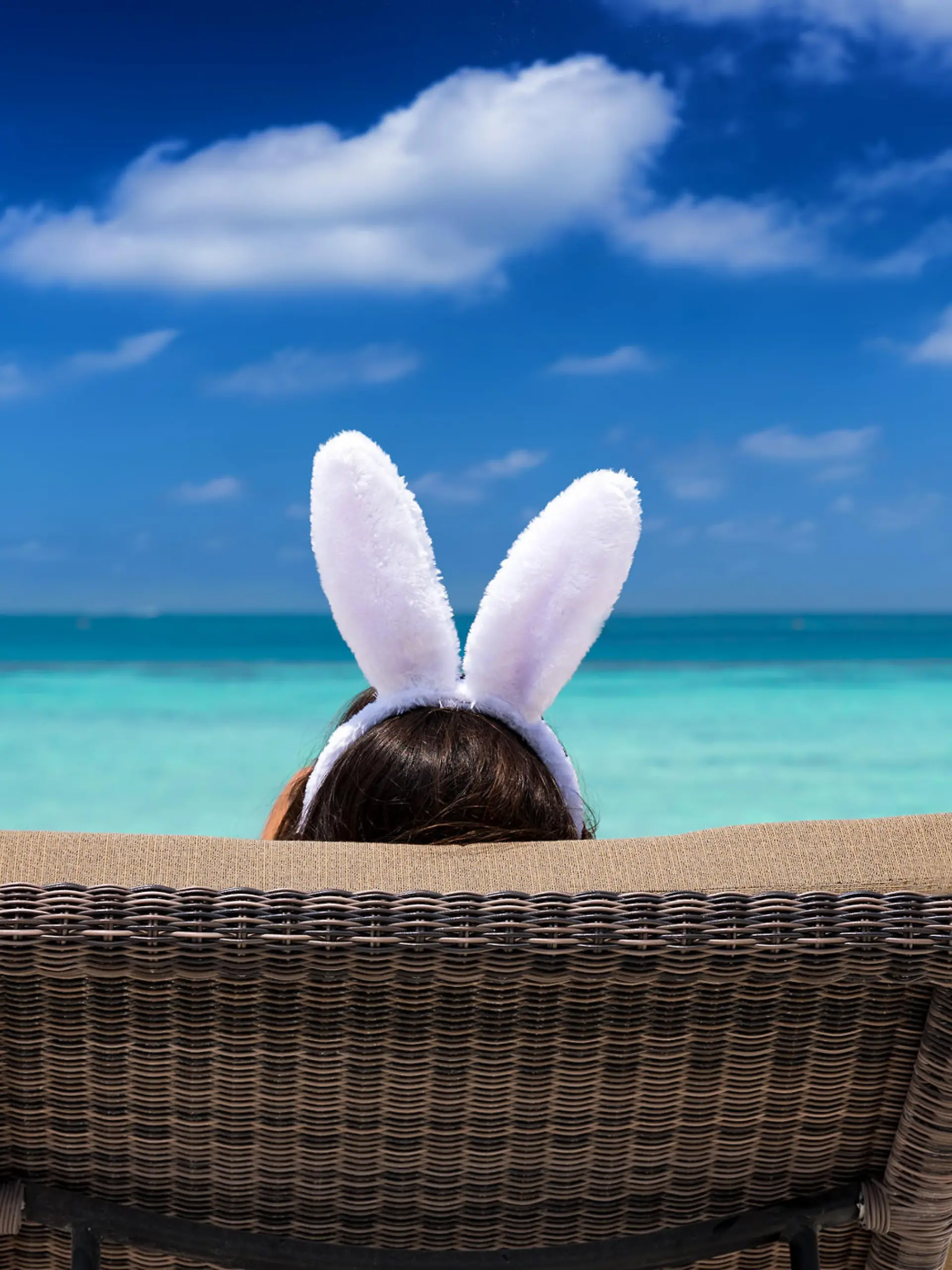 Easter travel concept: Woman with bunny ears on a tropical beach