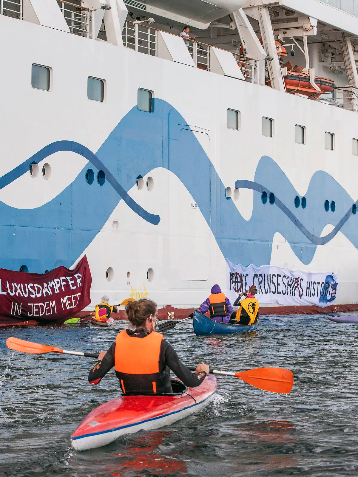 17.06.2023, Mecklenburg-Vorpommern, Rostock-Warnemünde: Klimaaktivisten versuchen auf Kanus und aufblasbaren Booten das Kreuzfahrtschiff «Aida Diva» am Auslaufen zu hindern. Die Aktivisten haben eine Aktion gegen den Kreuzfahrttourismus gestartet. Foto: Frank Hormann/dpa +++ dpa-Bildfunk +++