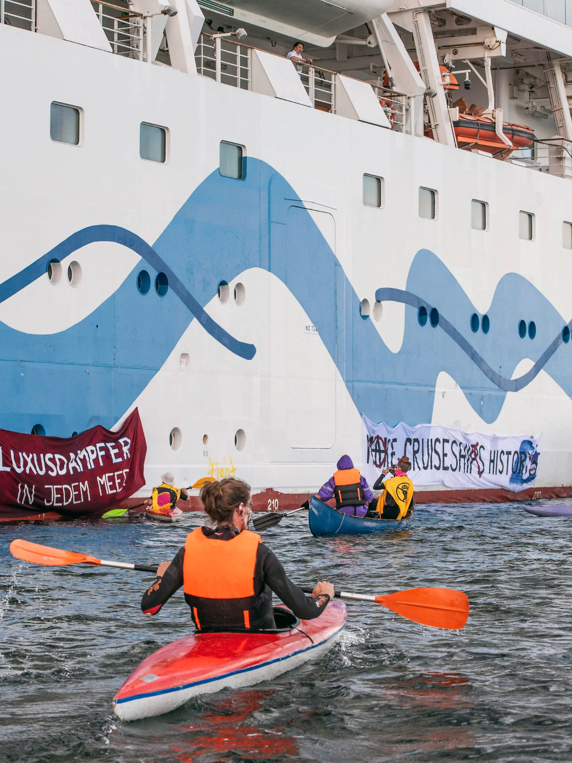 17.06.2023, Mecklenburg-Vorpommern, Rostock-Warnemünde: Klimaaktivisten versuchen auf Kanus und aufblasbaren Booten das Kreuzfahrtschiff «Aida Diva» am Auslaufen zu hindern. Die Aktivisten haben eine Aktion gegen den Kreuzfahrttourismus gestartet. Foto: Frank Hormann/dpa +++ dpa-Bildfunk +++