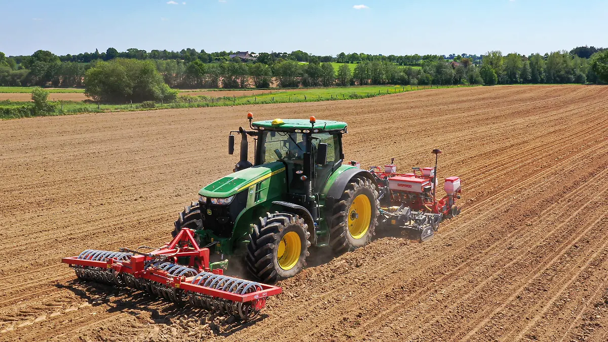 Ein Traktor samt Frontpacker pflügt ein Feld (Symbolbild).