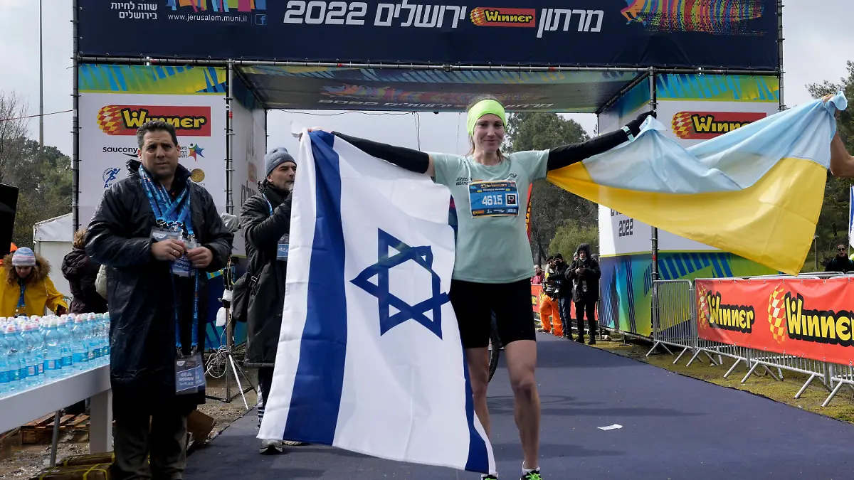 25.03.2022, Israel, Jerusalem: Valentyna Veretska, Läuferin aus der Ukraine, steht mit der ukrainischen und der israelischen Fahne, nachdem sie den ersten Platz bei den Frauen im Jerusalem-Marathon gewonnen hat. Die 31-jährige Veretska nahm an dem Rennen teil, nachdem sie mit ihrer 11-jährigen Tochter kurz nach dem Einmarsch Russlands in die Ukraine am 24. Februar geflohen war. Foto: Mahmoud Illean/AP/dpa +++ dpa-Bildfunk +++