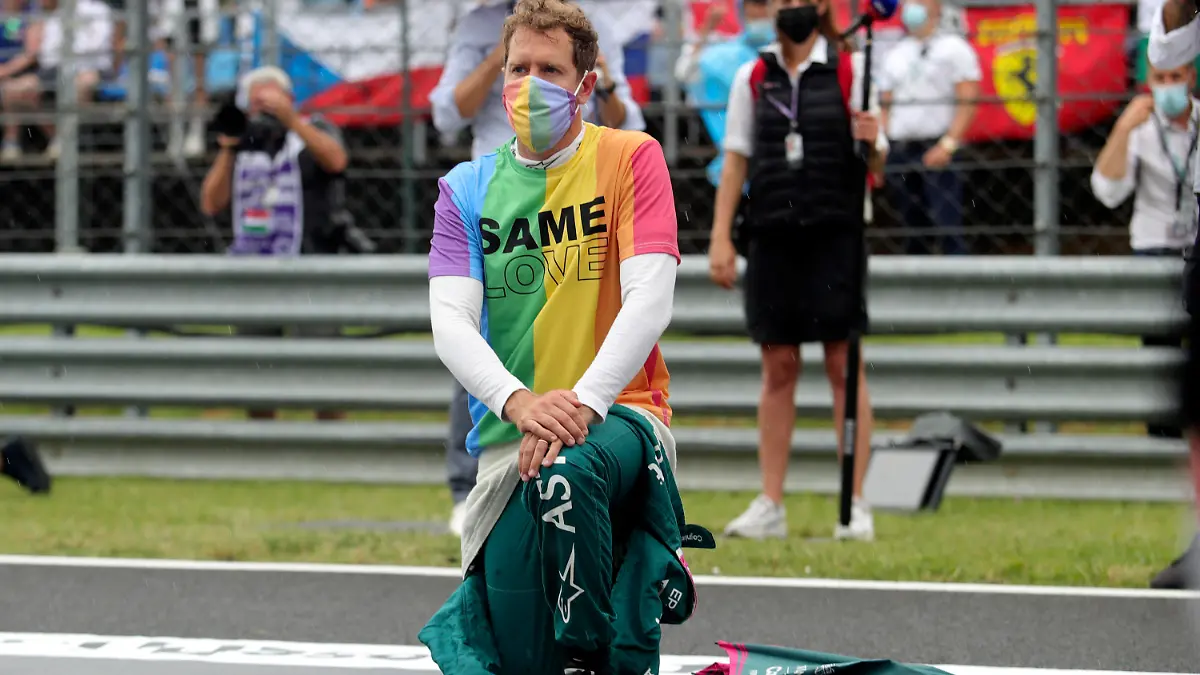 ARCHIV - 01.08.2021, Ungarn, Mogyorod: Motorsport: Formel-1-Weltmeisterschaft, Großer Preis von Ungarn, Rennen: Sebastian Vettel aus Deutschland vom Team Aston-Martin kniet vor dem Rennen auf der Rennstrecke zur Unterstützung der Black-Lives-Matter-Bewegung nieder und trägt eine T-Shirt in Regenbogenfarben. Der Hesse hat seinen Vertrag mit Aston Martin für die kommende Saison verlängert (zu dpa «Zweifel ausgeräumt: Vettel fährt weiter für Aston Martin») Foto: Florion Goga/Pool Reuters/AP/dpa +++ dpa-Bildfunk +++