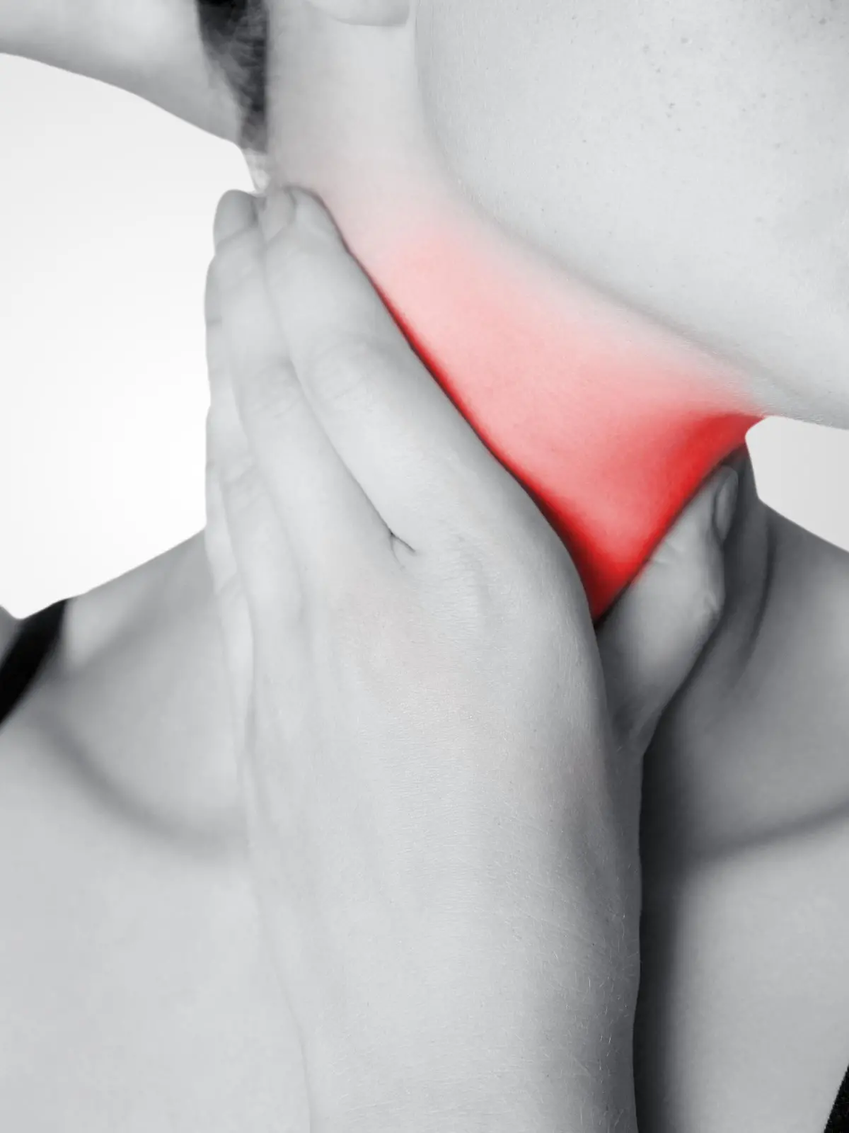 Closeup view of a young woman with pain on neck or thyroid gland on gray background. Black and white photo with red dot. || Modellfreigabe vorhanden