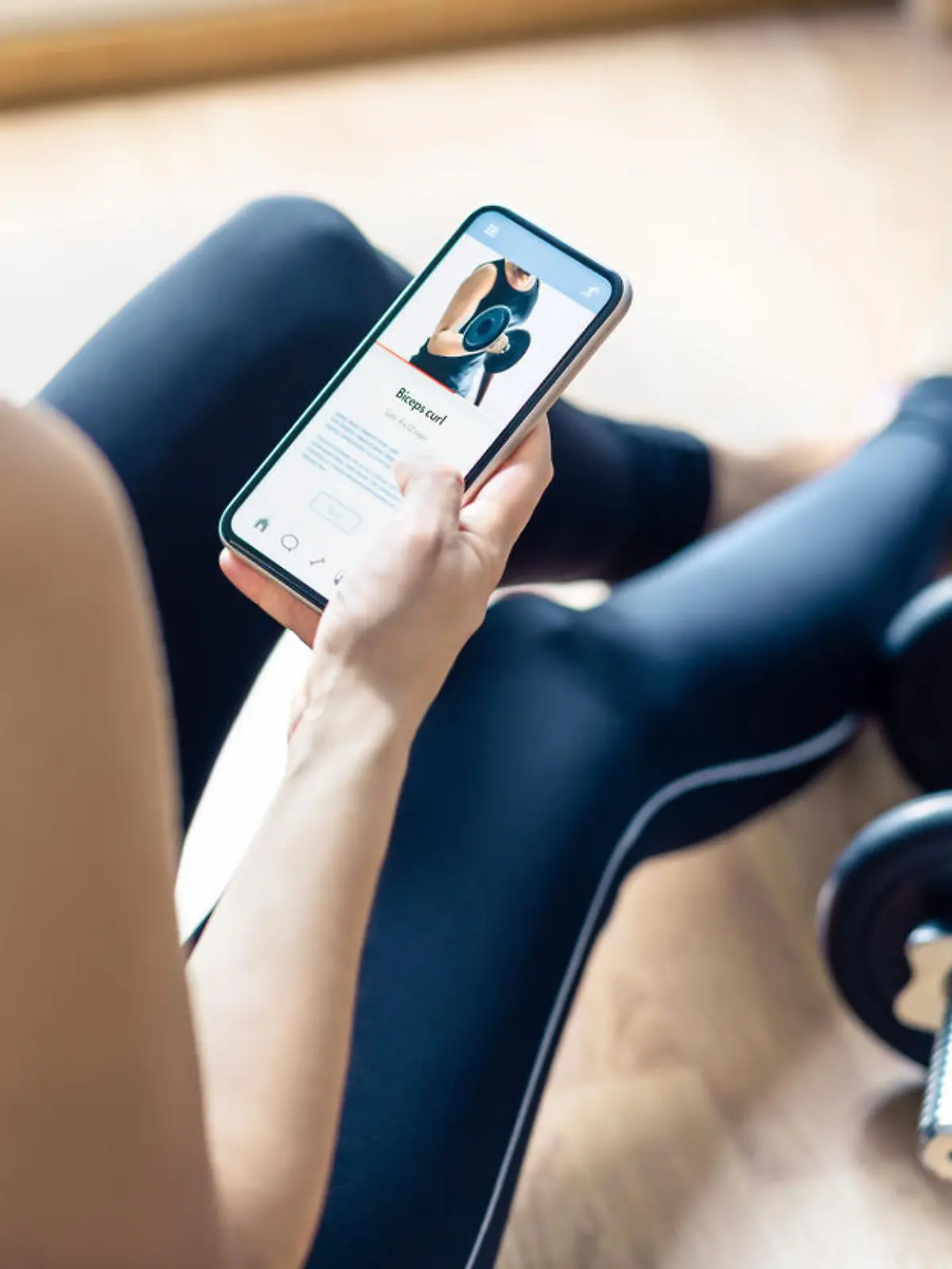 Home gym workout with online exercise app in phone. Fit woman watching training tutorial video or using digital personal trainer with smartphone. Internet coach. Sport routine or class in cellphone.