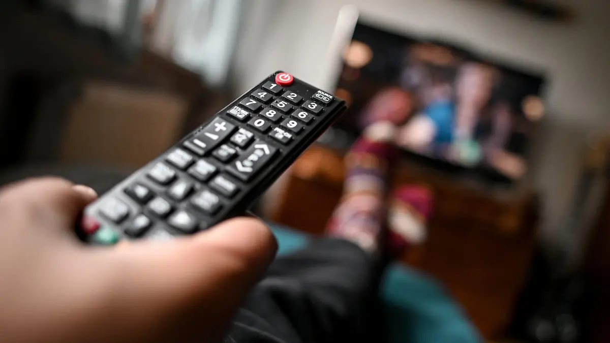 ARCHIV - 02.04.2020, Berlin: Ein junger Mann sitzt mit einer Fernbedienung vor dem Fernseher. (Illustration zu dpa "Studie: TV-Zuschauer wollen in Serien nicht an Corona erinnert werden") Foto: Britta Pedersen/dpa-Zentralbild/dpa +++ dpa-Bildfunk +++
