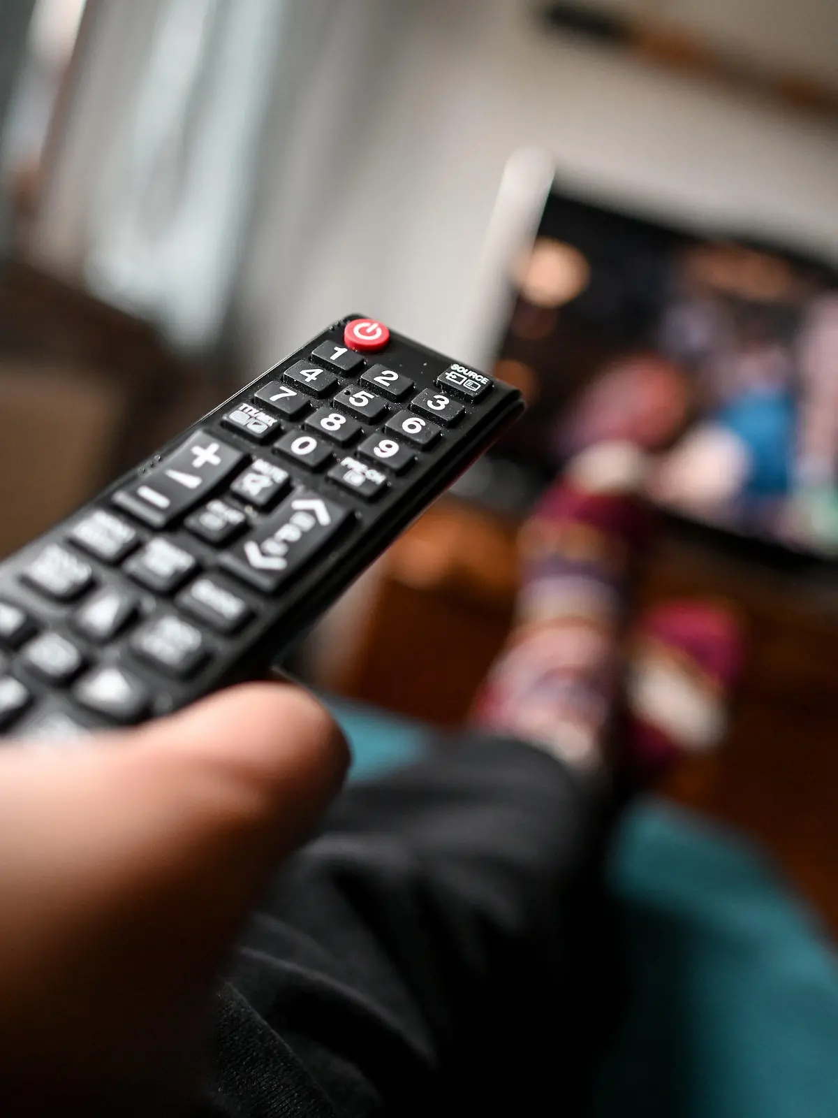 ARCHIV - 02.04.2020, Berlin: Ein junger Mann sitzt mit einer Fernbedienung vor dem Fernseher. (Illustration zu dpa "Studie: TV-Zuschauer wollen in Serien nicht an Corona erinnert werden") Foto: Britta Pedersen/dpa-Zentralbild/dpa +++ dpa-Bildfunk +++