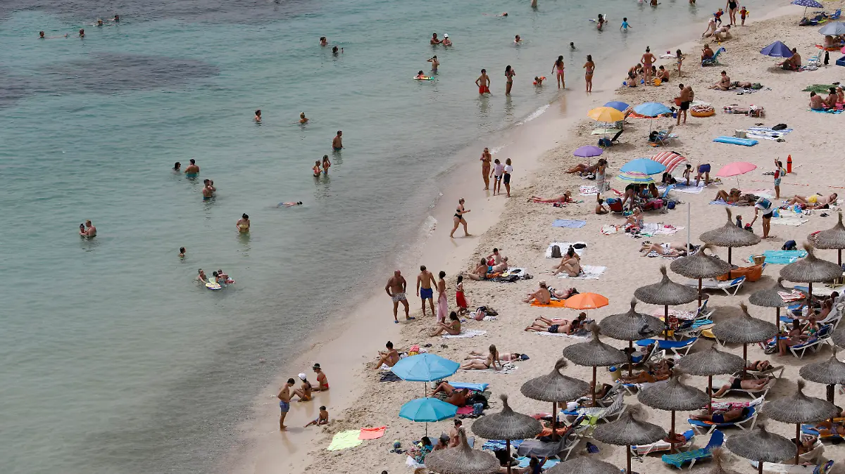 ARCHIV - 10.08.2021, Spanien, Calvia: Touristen genießen an einem Strand bei Puerto Portals auf Mallorca die Sonne und das Meer. Nach zwei Jahren der Corona-Pandemie ist die Reiselust der Menschen in Deutschland einer Umfrage zufolge groß. (zu dpa "Umfrage: Fast zwei Drittel der Menschen planen Urlaubsreise") Foto: Clara Margais/dpa +++ dpa-Bildfunk +++