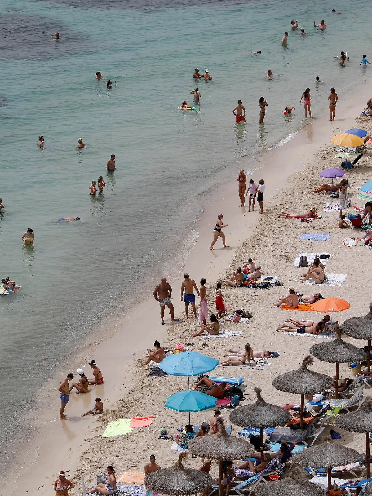 ARCHIV - 10.08.2021, Spanien, Calvia: Touristen genießen an einem Strand bei Puerto Portals auf Mallorca die Sonne und das Meer. Nach zwei Jahren der Corona-Pandemie ist die Reiselust der Menschen in Deutschland einer Umfrage zufolge groß. (zu dpa "Umfrage: Fast zwei Drittel der Menschen planen Urlaubsreise") Foto: Clara Margais/dpa +++ dpa-Bildfunk +++