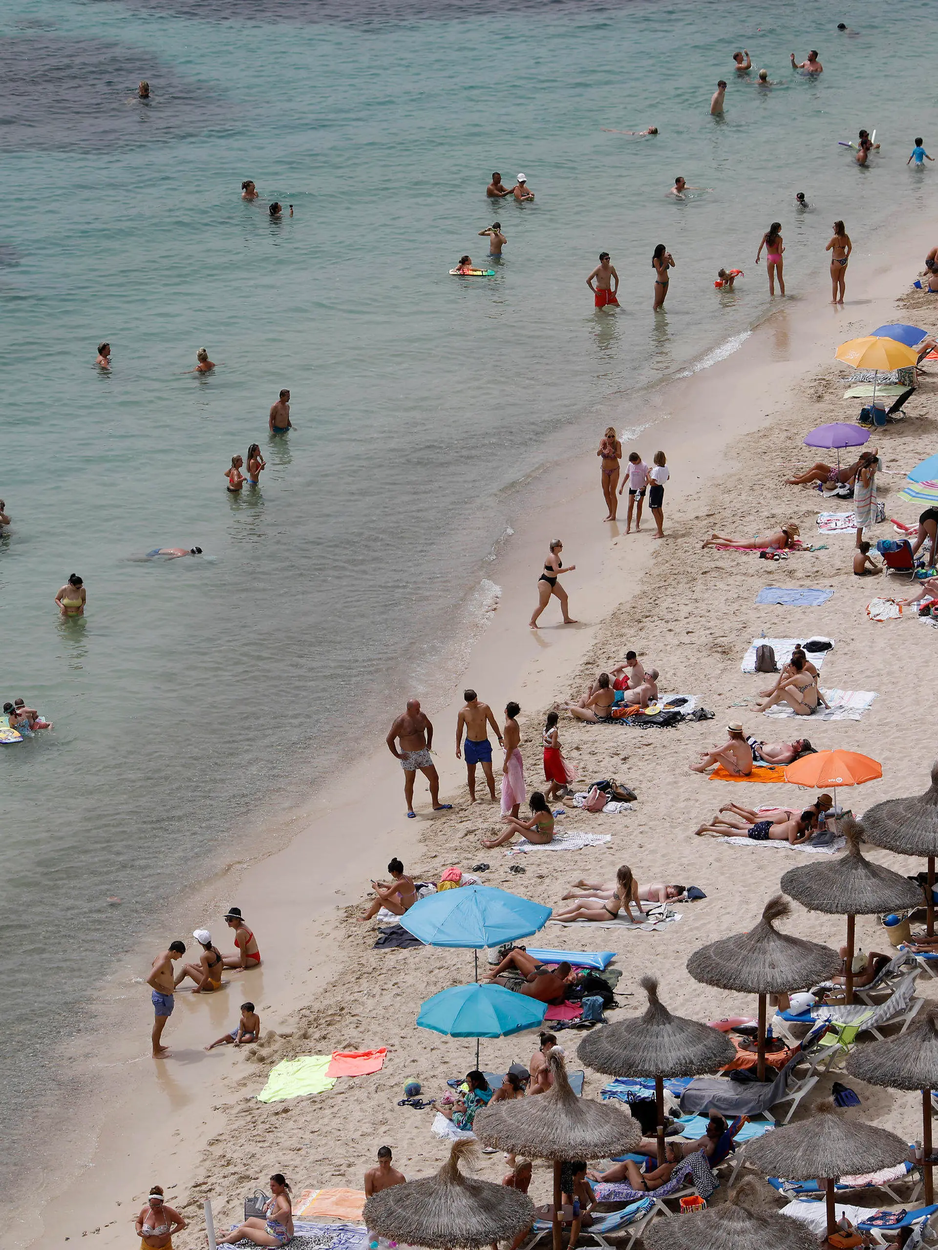 ARCHIV - 10.08.2021, Spanien, Calvia: Touristen genießen an einem Strand bei Puerto Portals auf Mallorca die Sonne und das Meer. Nach zwei Jahren der Corona-Pandemie ist die Reiselust der Menschen in Deutschland einer Umfrage zufolge groß. (zu dpa "Umfrage: Fast zwei Drittel der Menschen planen Urlaubsreise") Foto: Clara Margais/dpa +++ dpa-Bildfunk +++