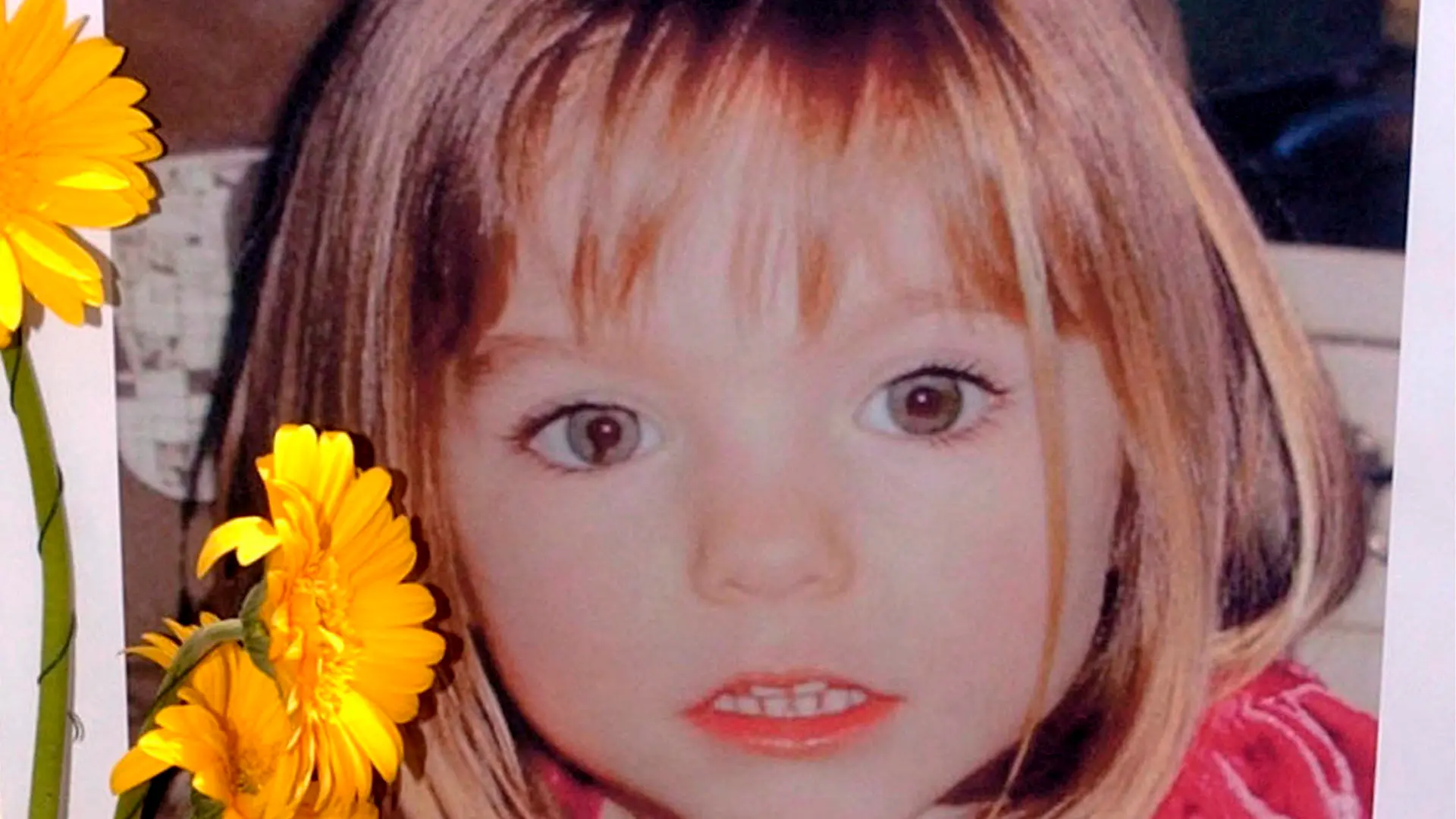 ARCHIV - 12.05.2007, Portugal, Lagos: Blumen stehen vor einem Bild, das die verschwundenen Madeleine McCann (Maddie) auf einem Foto zeigt, das ihre Eltern im Zusammenhang mit dem Verschwinden des Kindes veröffentlich haben. (zu dpa "Verdächtiger im Fall Maddie: Ermittlungen nach Anhörung im Gericht") Foto: Luis Forra/LUSA FILE/dpa +++ dpa-Bildfunk +++