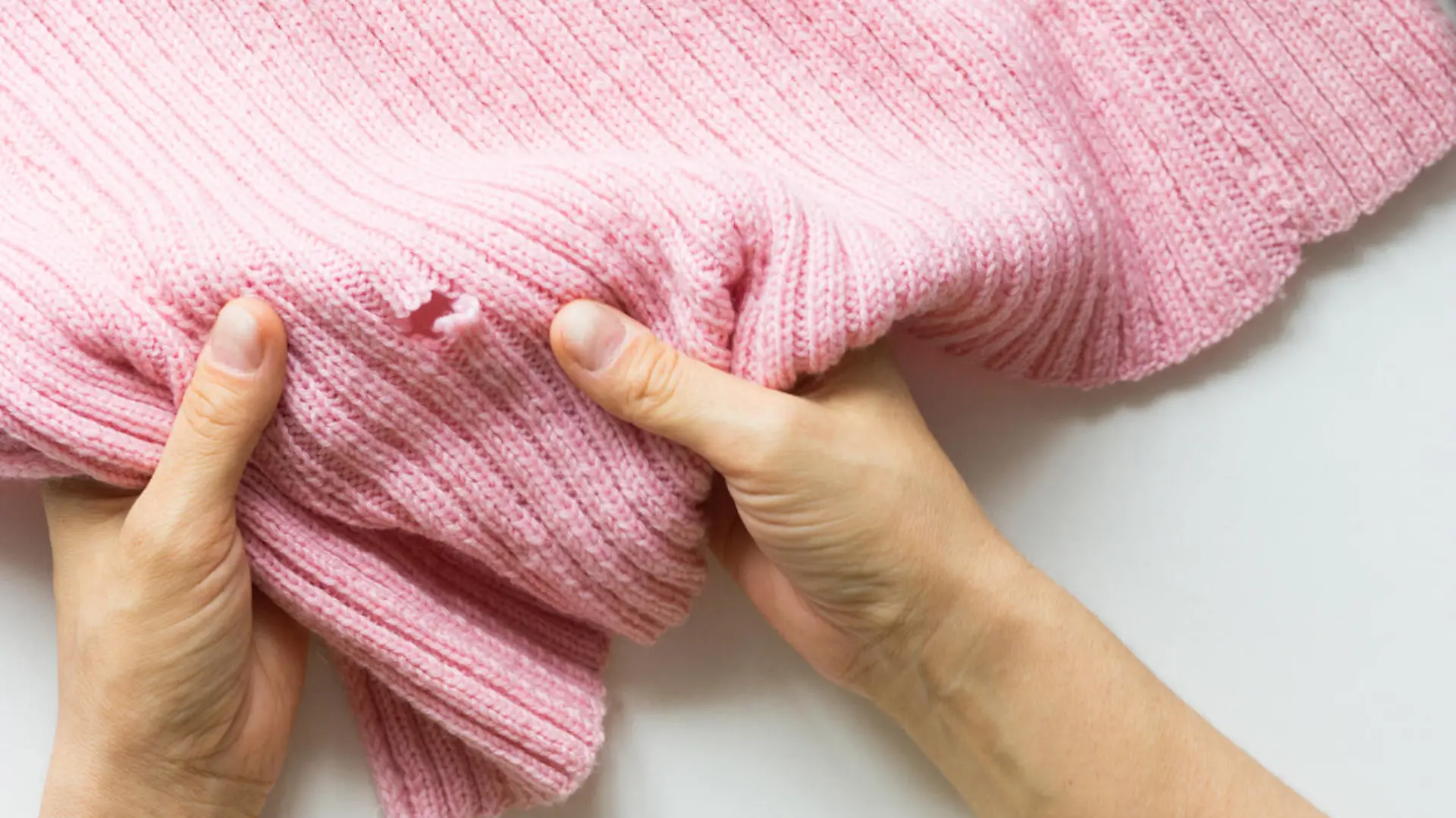 Woman hands holding the knitted thing with hole made by mole