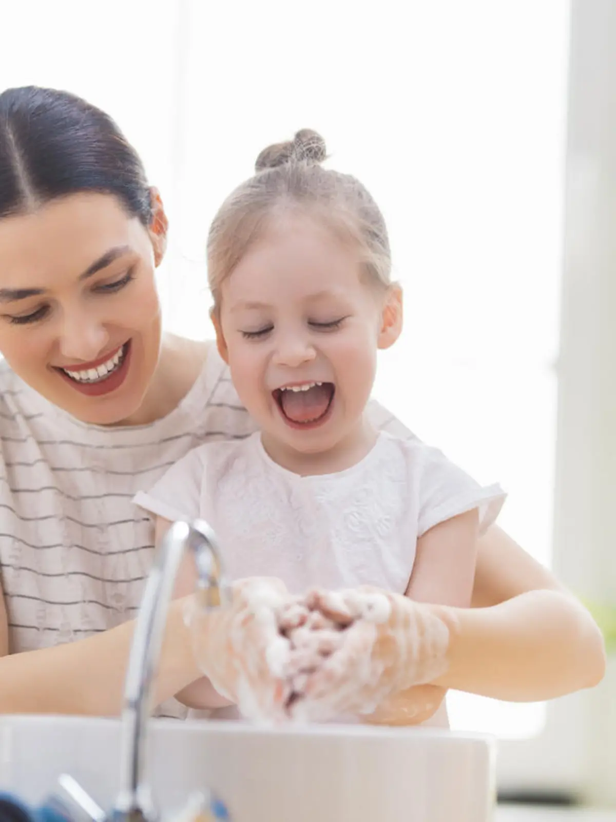 A cute little girl and her mother are washing their hands. Protection against infections and viruses.
