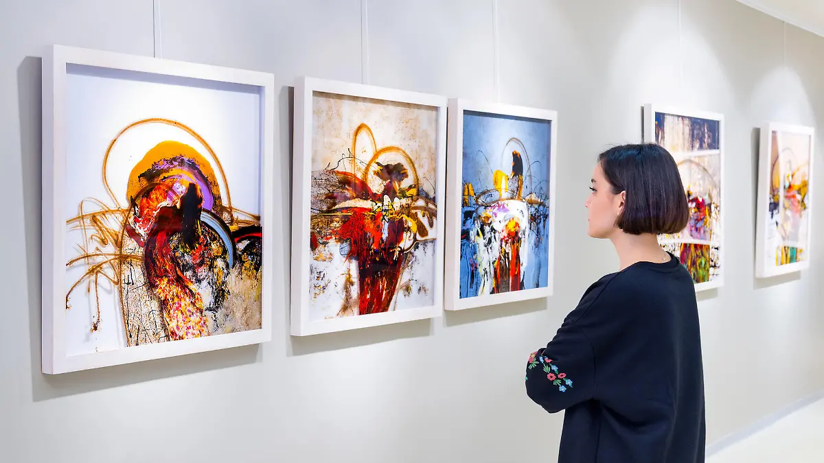 In a art gallery young woman visits an art exhibition and watches artist's collection.