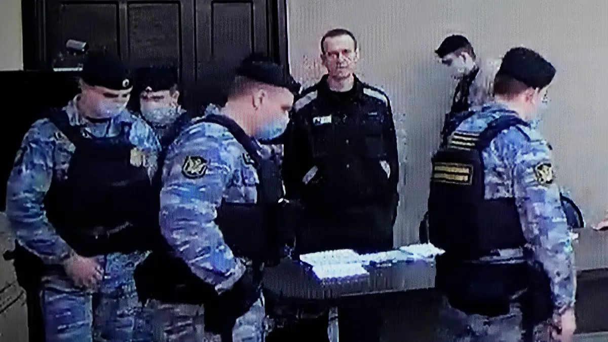 22.03.2022, Russland, Pokrov: Der russische Oppositionsführer Alexej Nawalny (M) ist auf einem Standbild aus einem Video zu sehen. Der Link zu dem Video wurde von der russischen Strafvollzugsbehörde zur Verfügung gestellt. Nawalny steht während einer Gerichtssitzung in Pokrow, Region Wladimir, etwa 100 Kilometer östlich von Moskau, neben Strafvollzugsbediensteten. Die russischen Behörden streben eine 13-jährige Haftstrafe für den Oppositionsführer an. Foto: Alexander Zemlianichenko/AP/dpa +++ dpa-Bildfunk +++