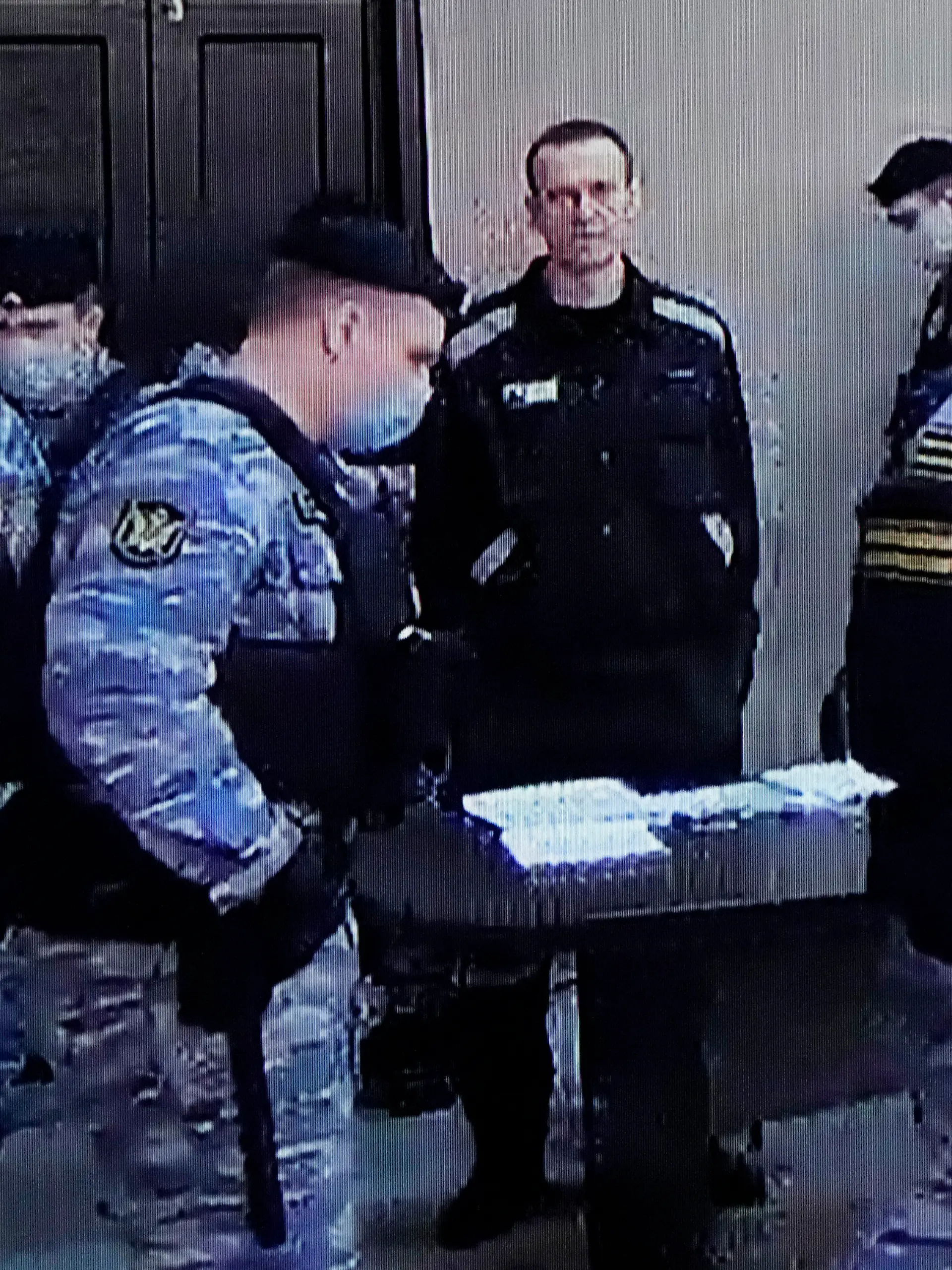 22.03.2022, Russland, Pokrov: Der russische Oppositionsführer Alexej Nawalny (M) ist auf einem Standbild aus einem Video zu sehen. Der Link zu dem Video wurde von der russischen Strafvollzugsbehörde zur Verfügung gestellt. Nawalny steht während einer Gerichtssitzung in Pokrow, Region Wladimir, etwa 100 Kilometer östlich von Moskau, neben Strafvollzugsbediensteten. Die russischen Behörden streben eine 13-jährige Haftstrafe für den Oppositionsführer an. Foto: Alexander Zemlianichenko/AP/dpa +++ dpa-Bildfunk +++